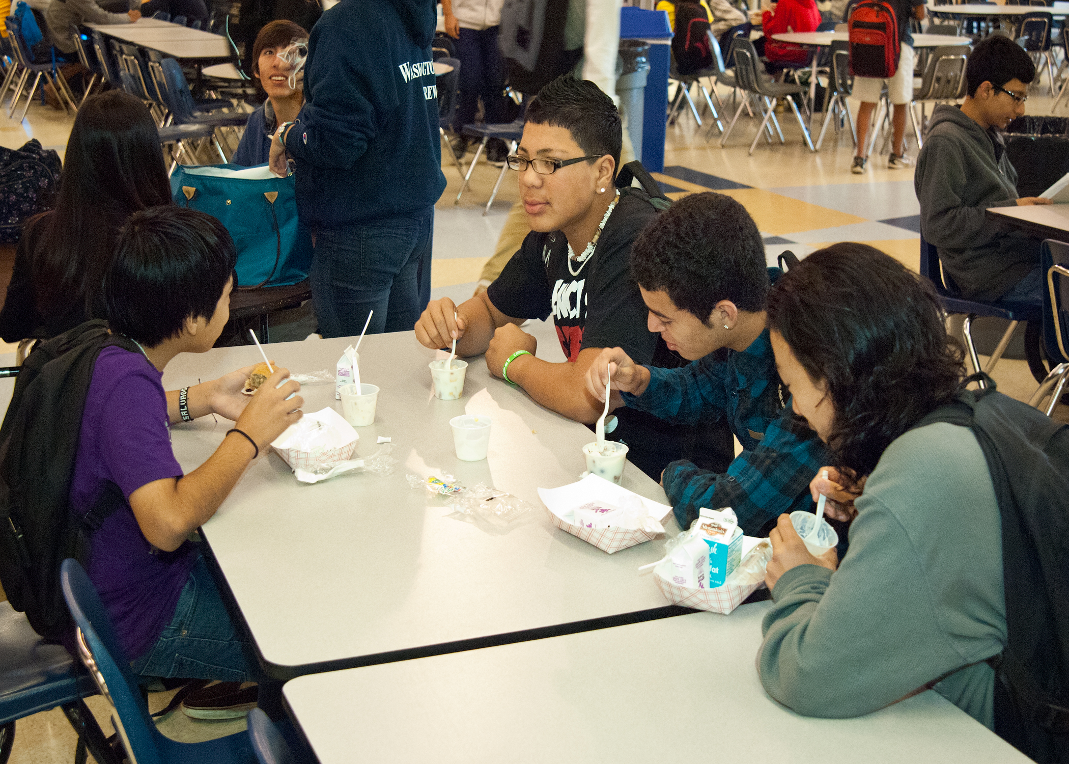Four students sit at a cafeteria table eating yogurt parfaits for breakfast.