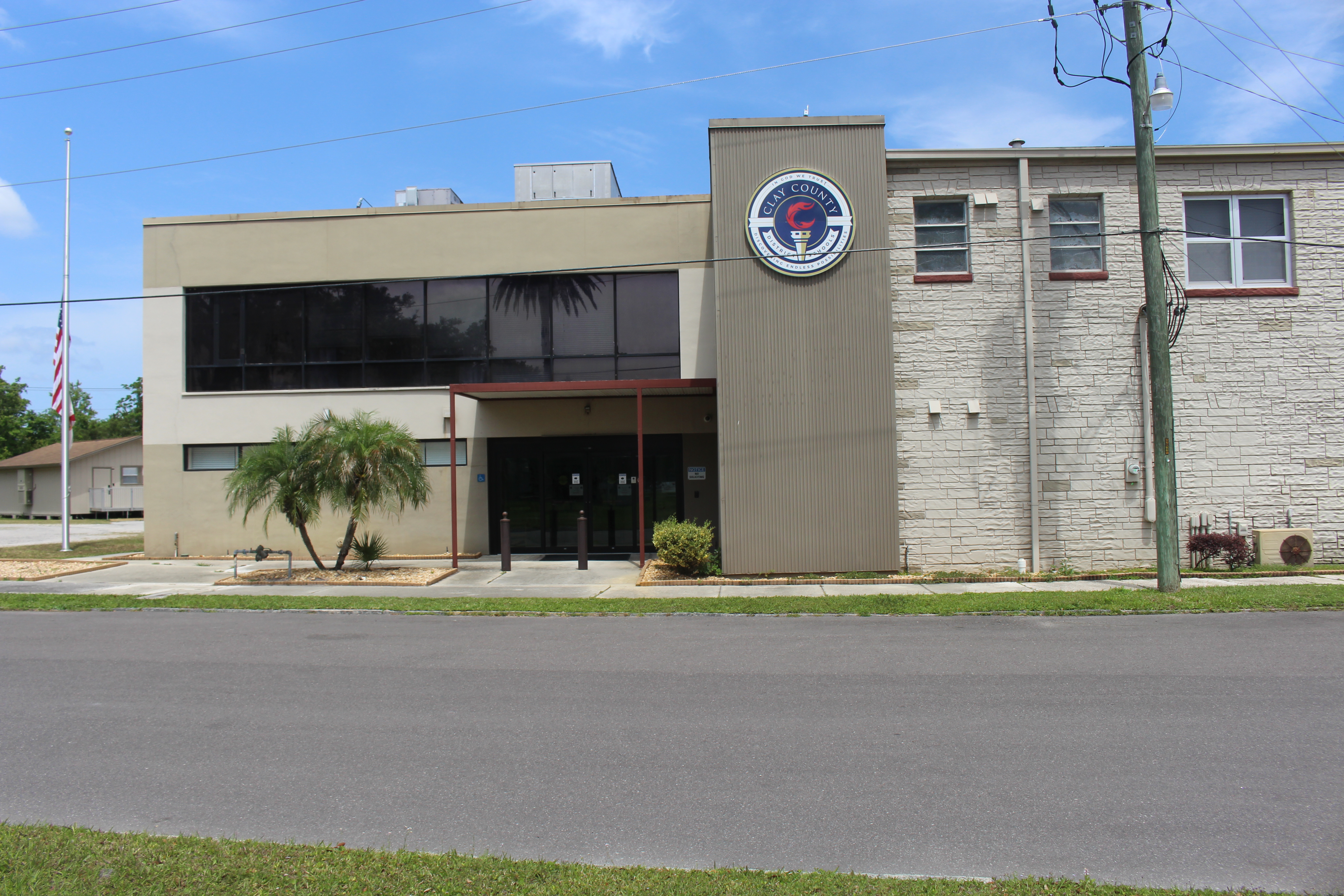 Two-story school district administrative building with a circular seal and American flag outside.