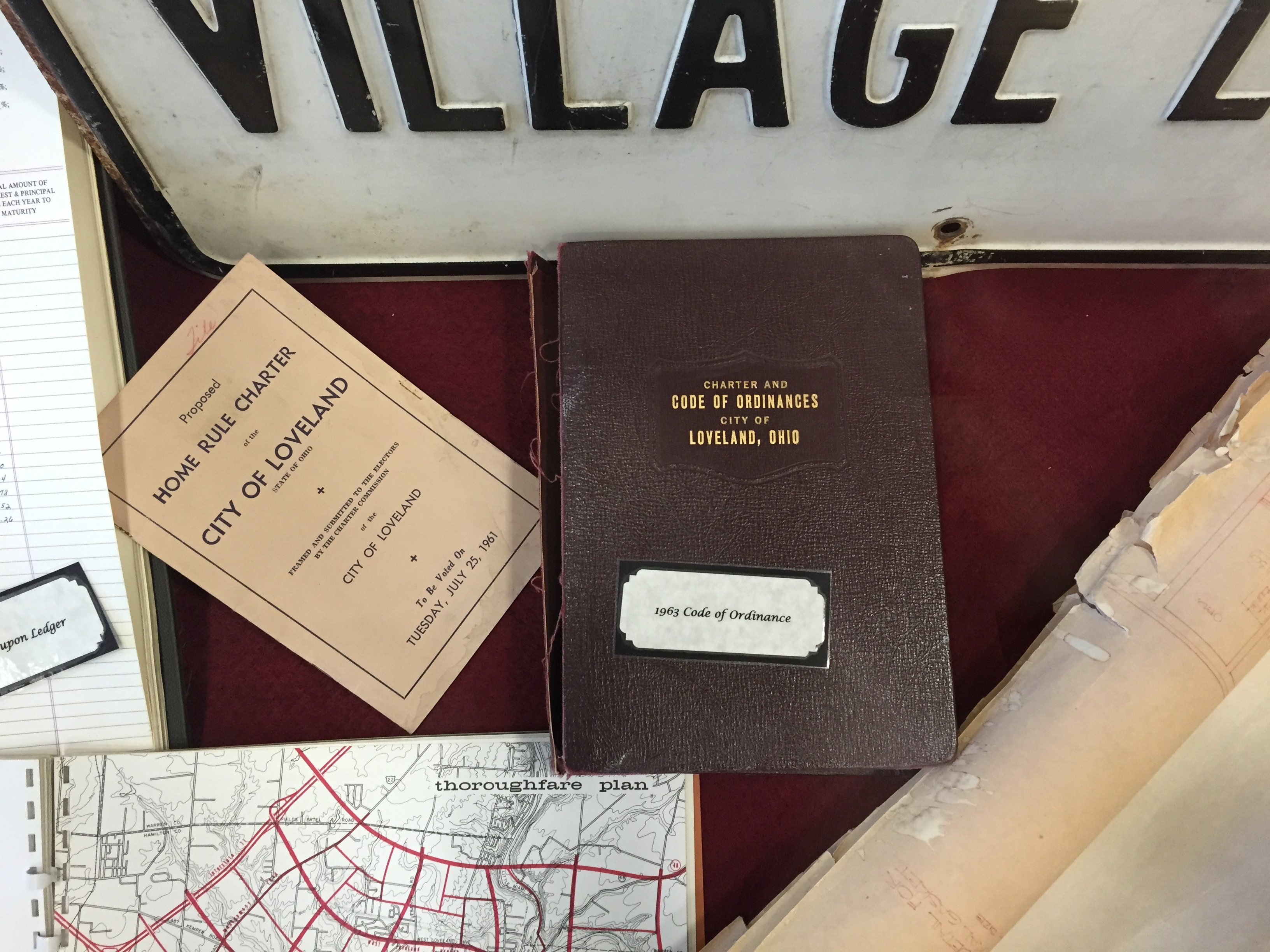 Display case holding bound ordinance books and a map at a city hall.