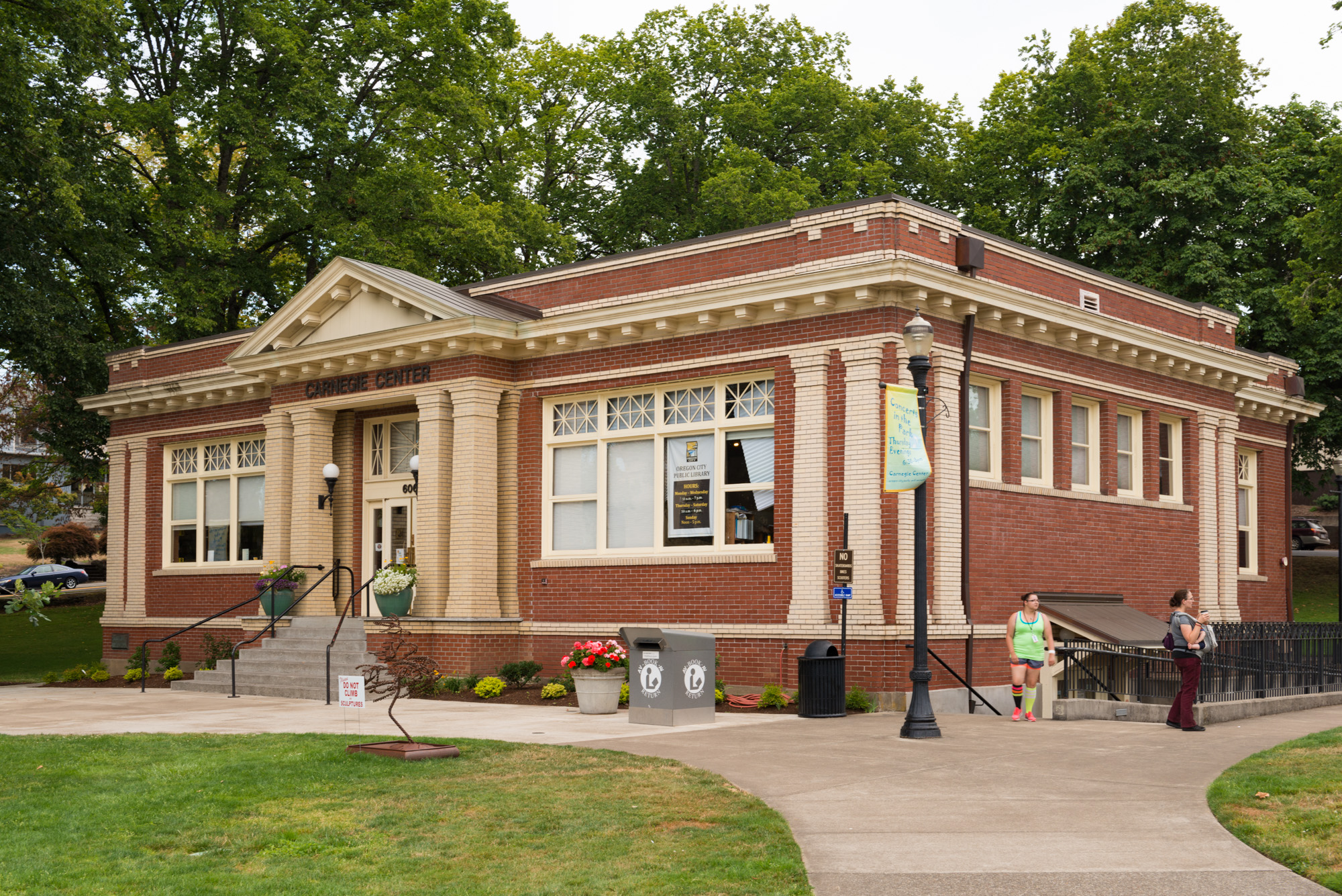 Red-brick neoclassical library building with classical columns, front steps, and mature trees.