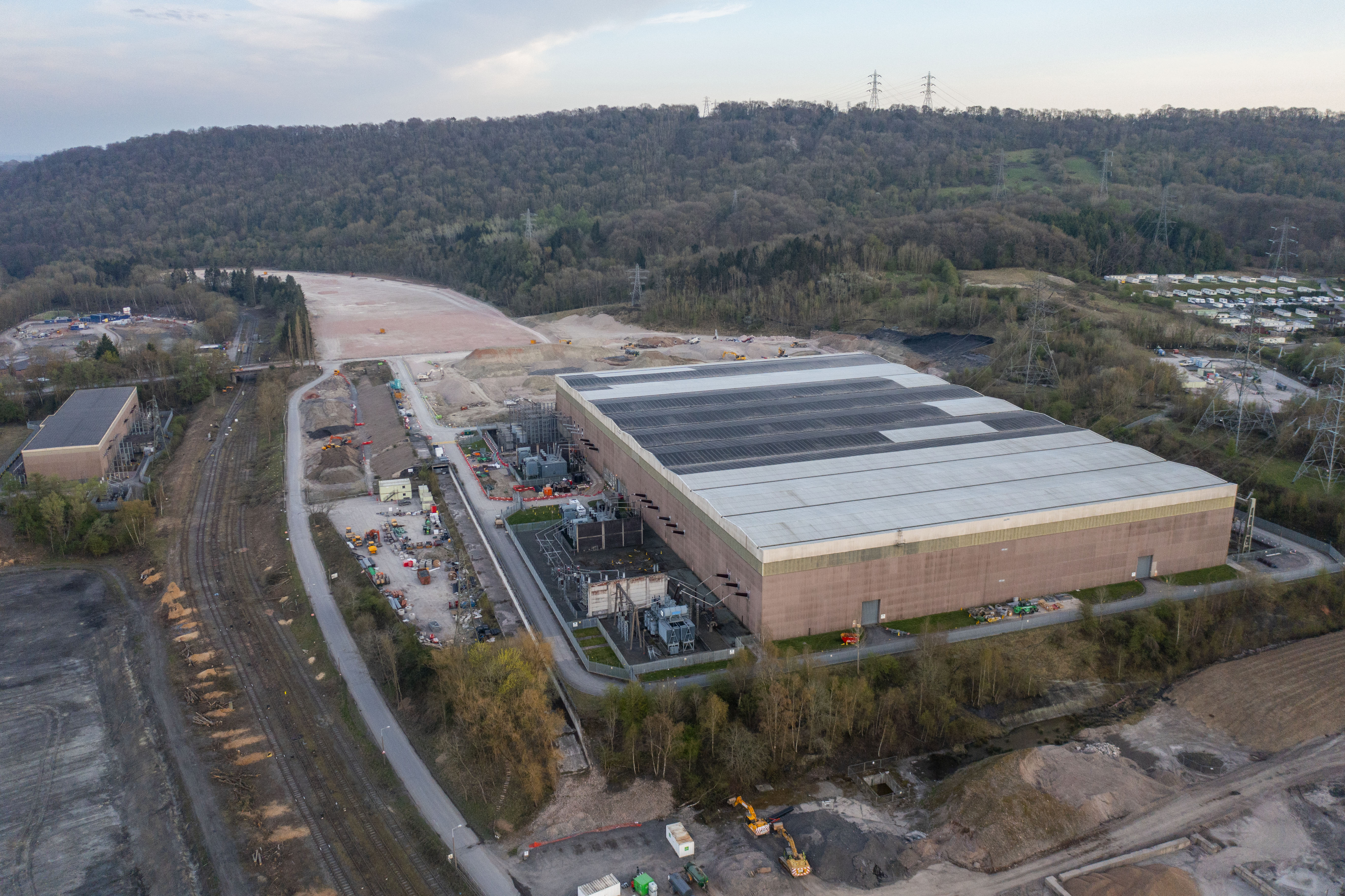 Aerial view of a large industrial building with adjacent electrical substation and rail lines.