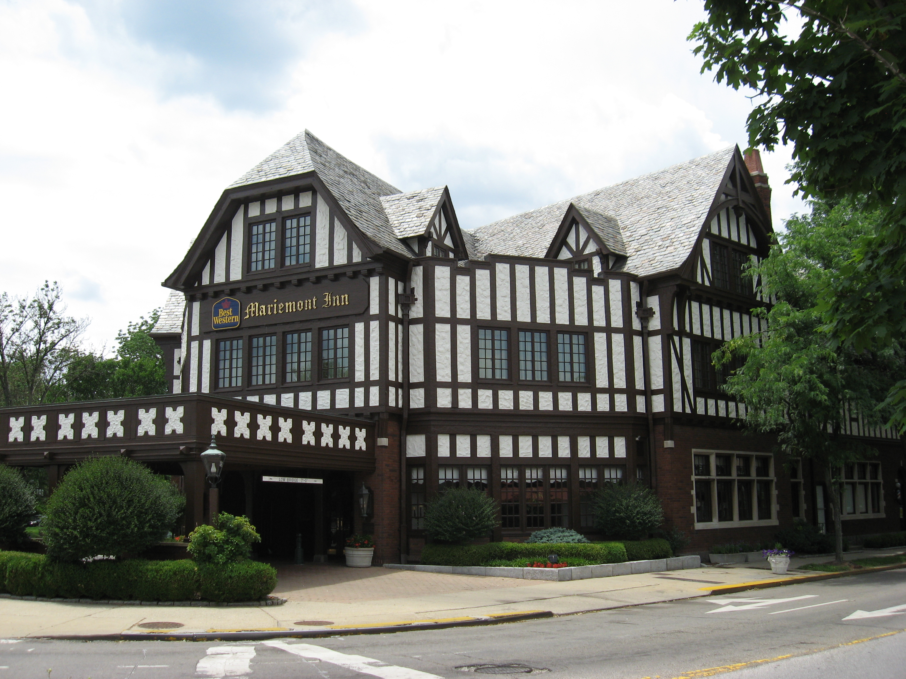 Tudor Revival building with half-timbering and a decorative white-railed walkway at a street corner.