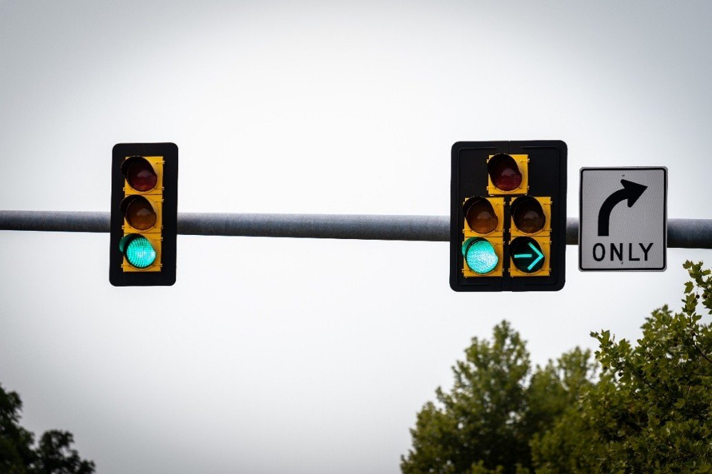 Two green traffic signals on an overhead pole, with a right-turn-only sign mounted beside them.