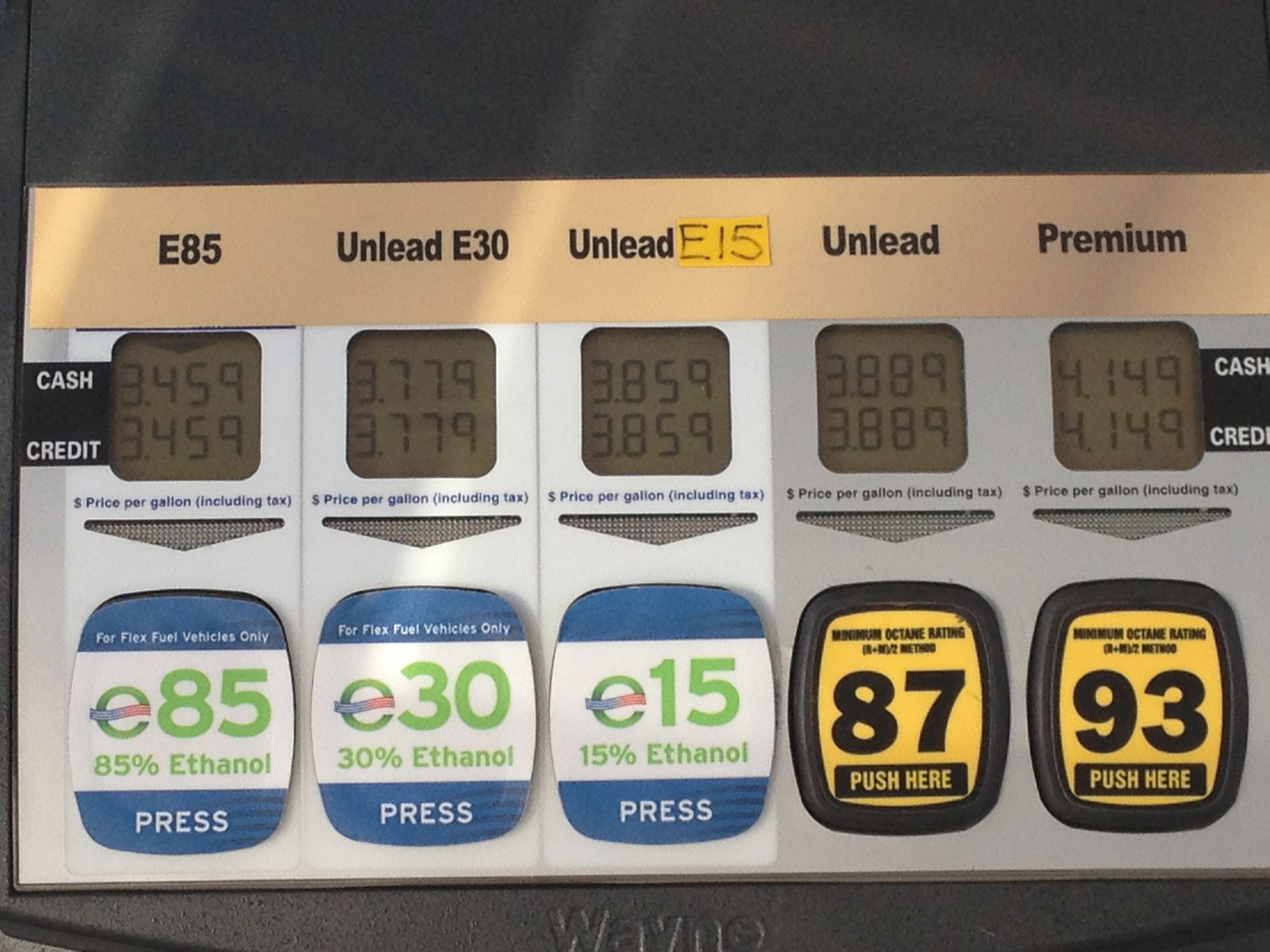 Close-up of a fuel pump display panel showing per-gallon prices for multiple gasoline grades.