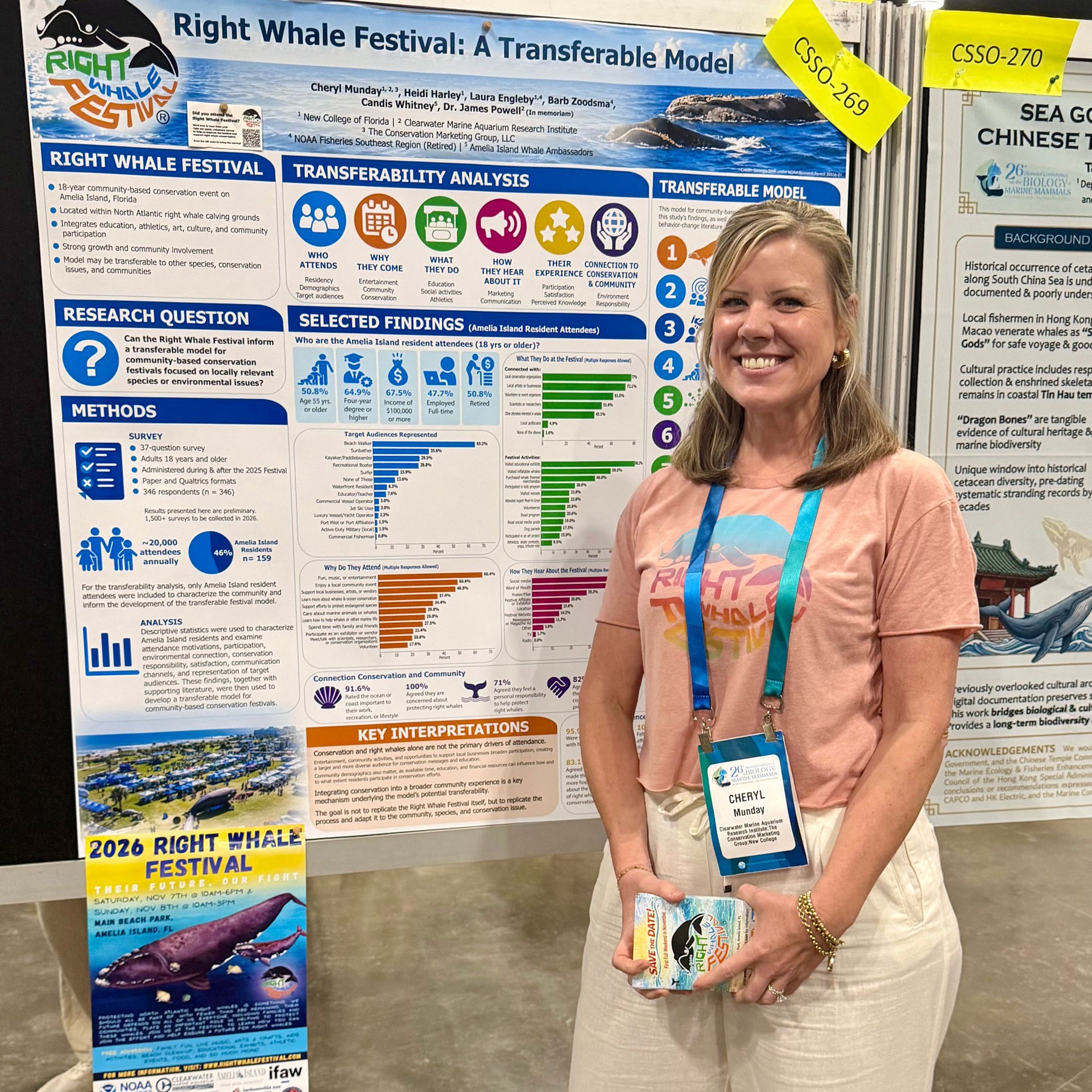 A smiling woman in a pink shirt stands in front of a large research poster at a conference.
