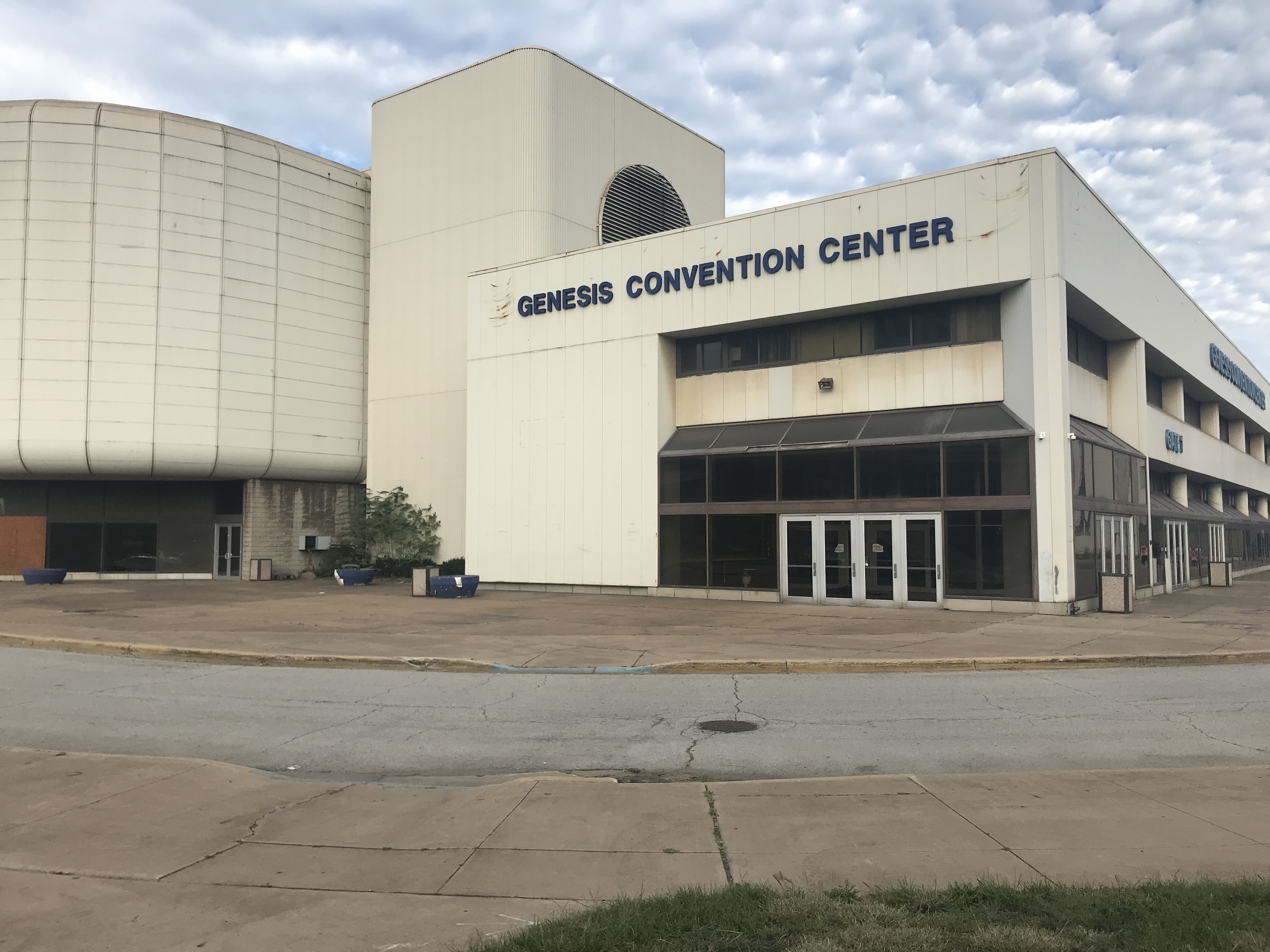 Large beige multi-story building with signage and an empty parking lot in front.