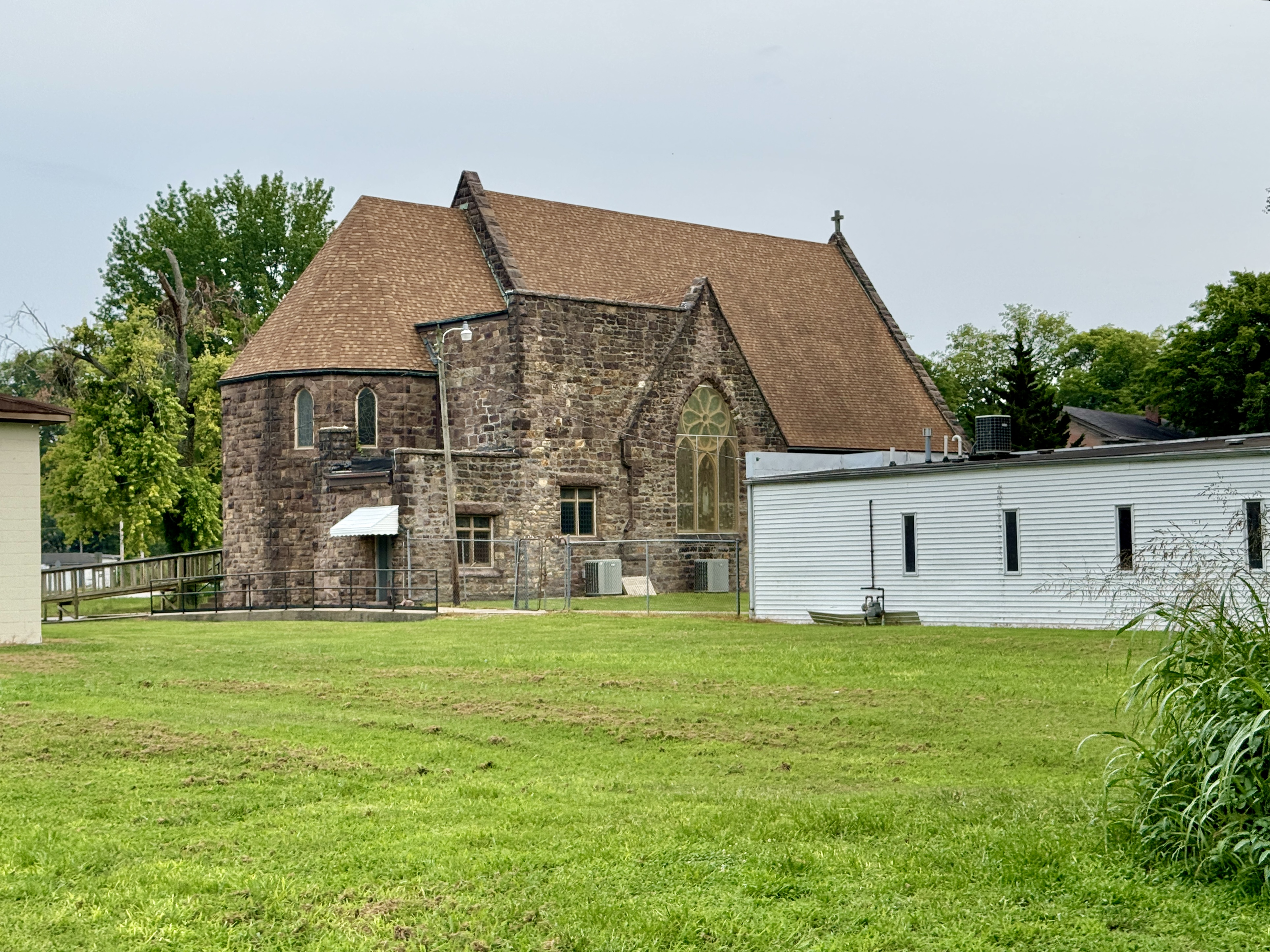 Gothic Revival stone church with gabled roof and stained glass windows on a green lawn.