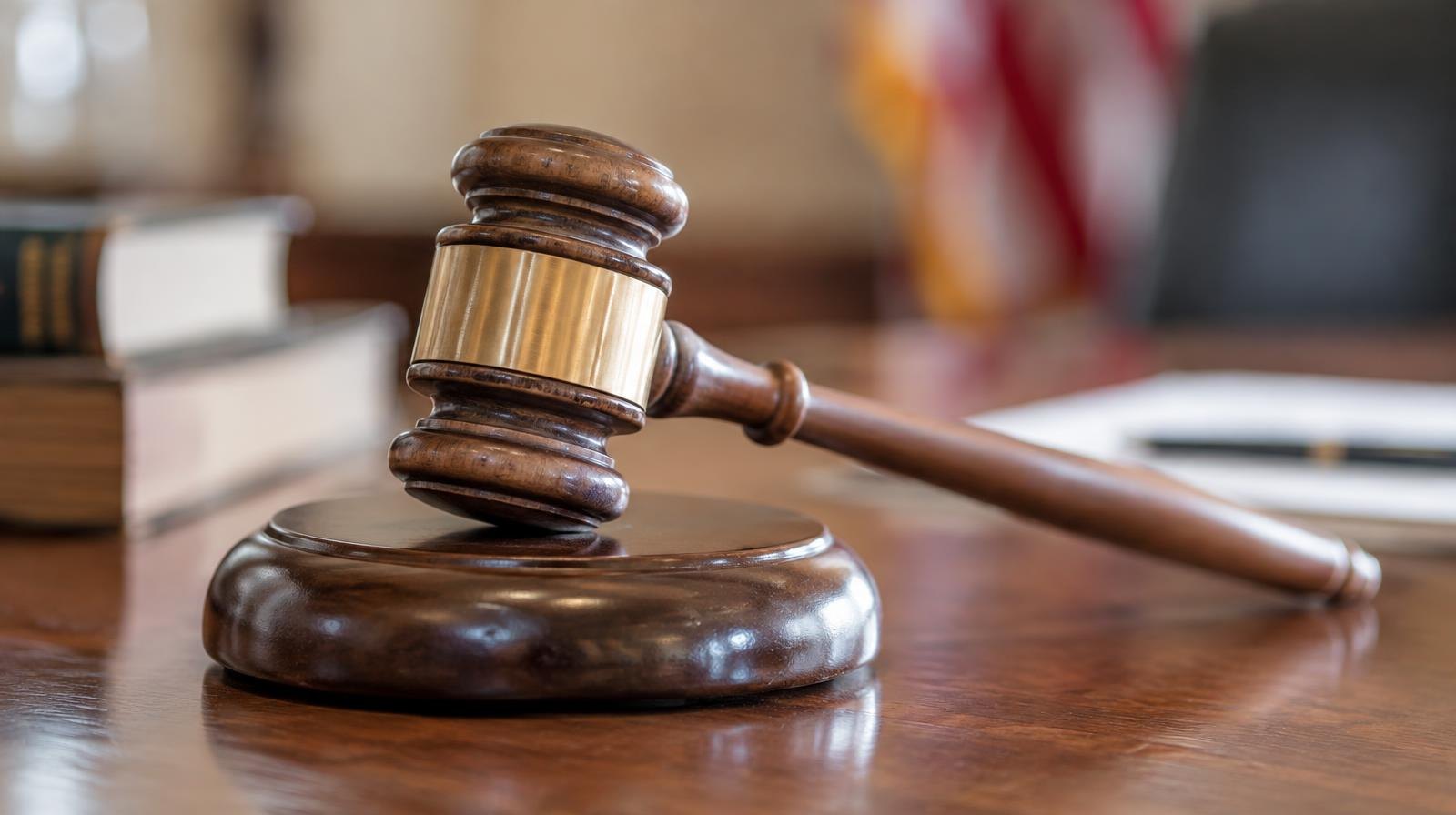 A wooden gavel resting on its sound block on a polished surface.