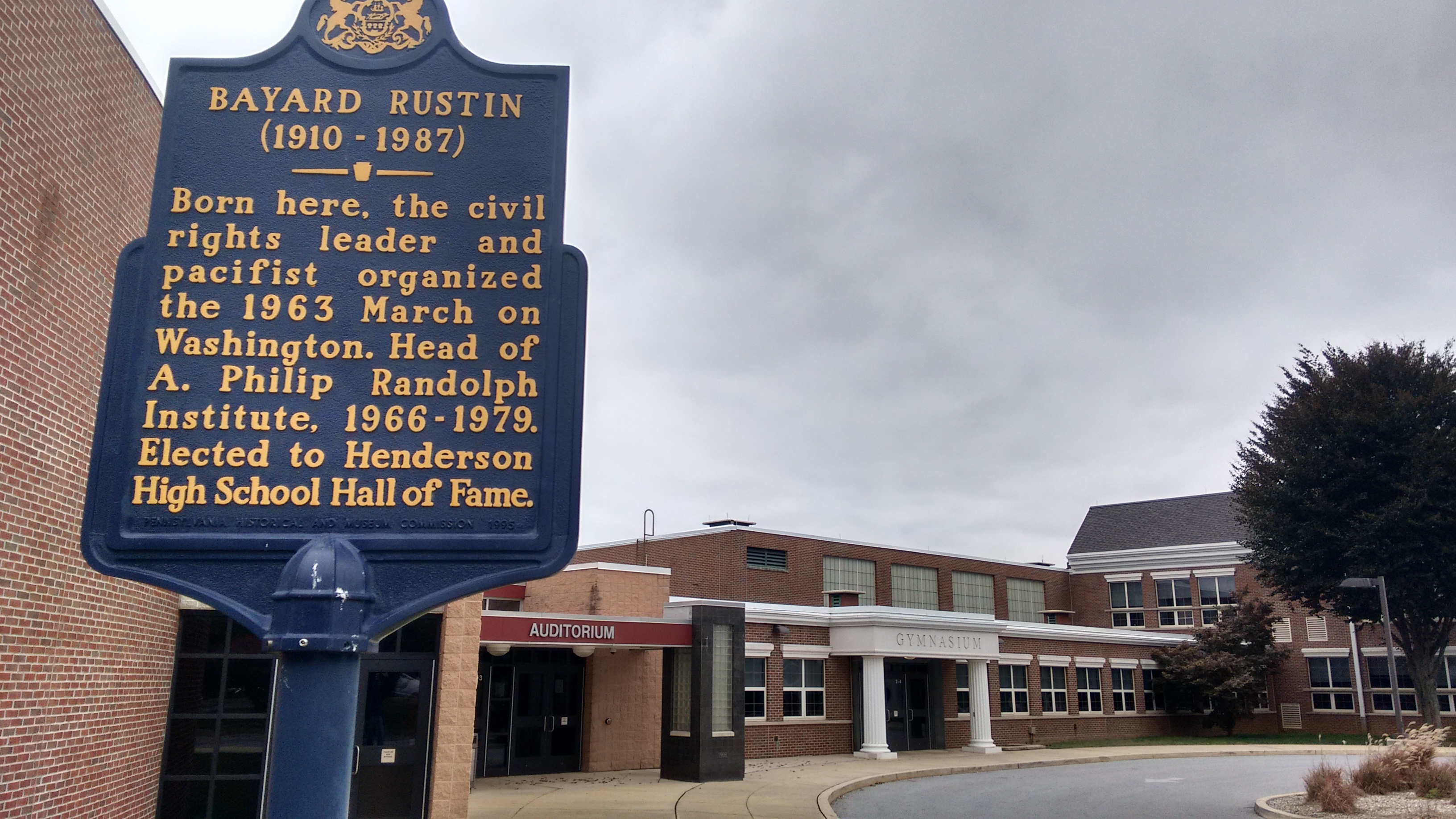 Brick school auditorium building with a Pennsylvania historical marker in front.