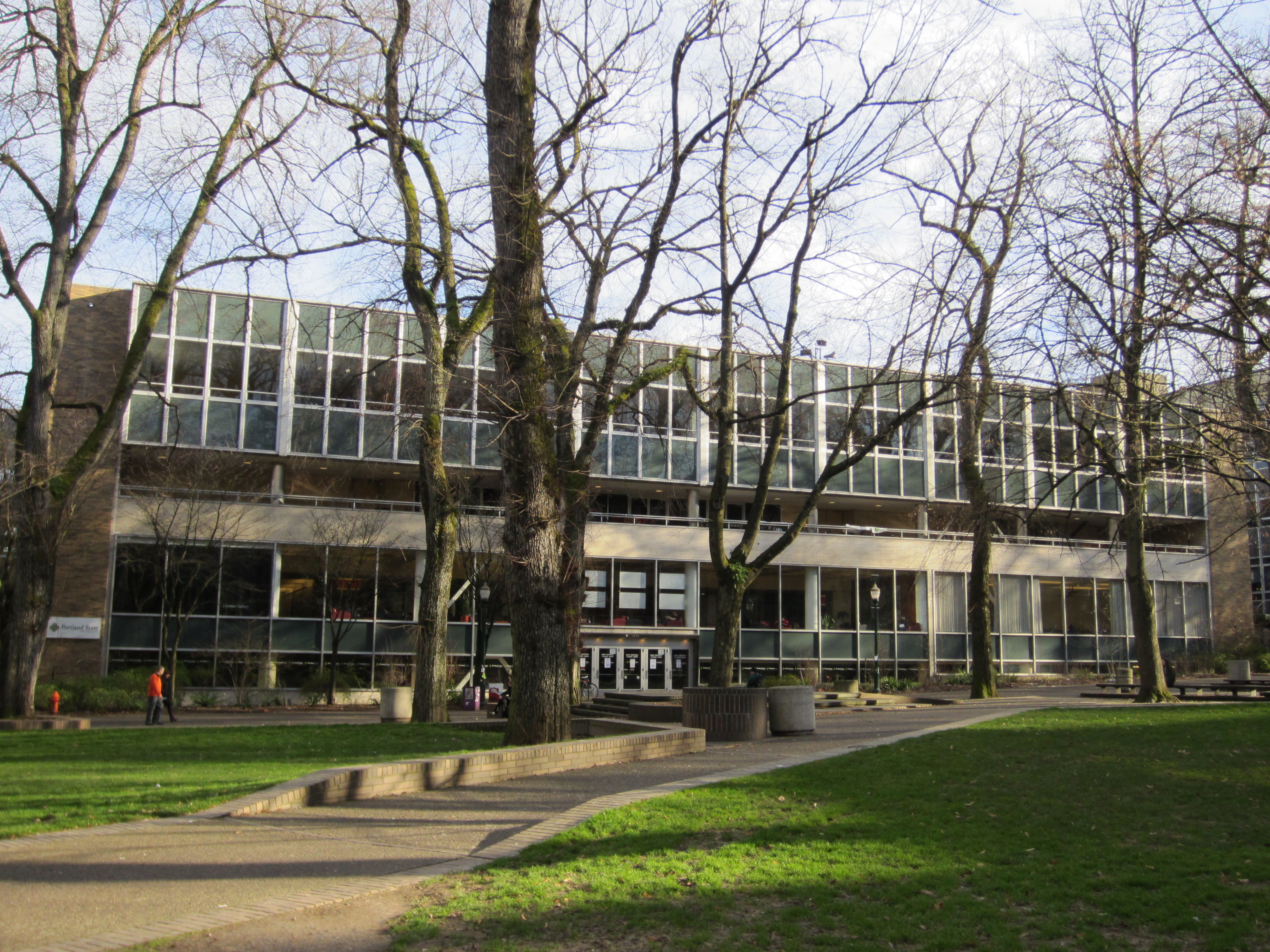 Modernist glass-and-brick building exterior surrounded by bare trees on a university campus.