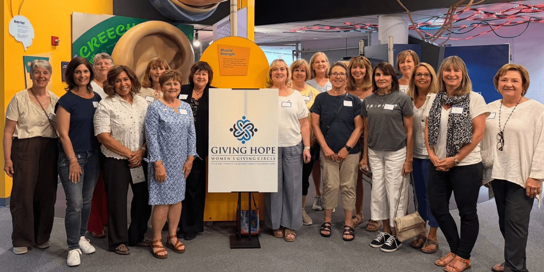 Group of about 15 women posing indoors in front of a Giving Hope sign.