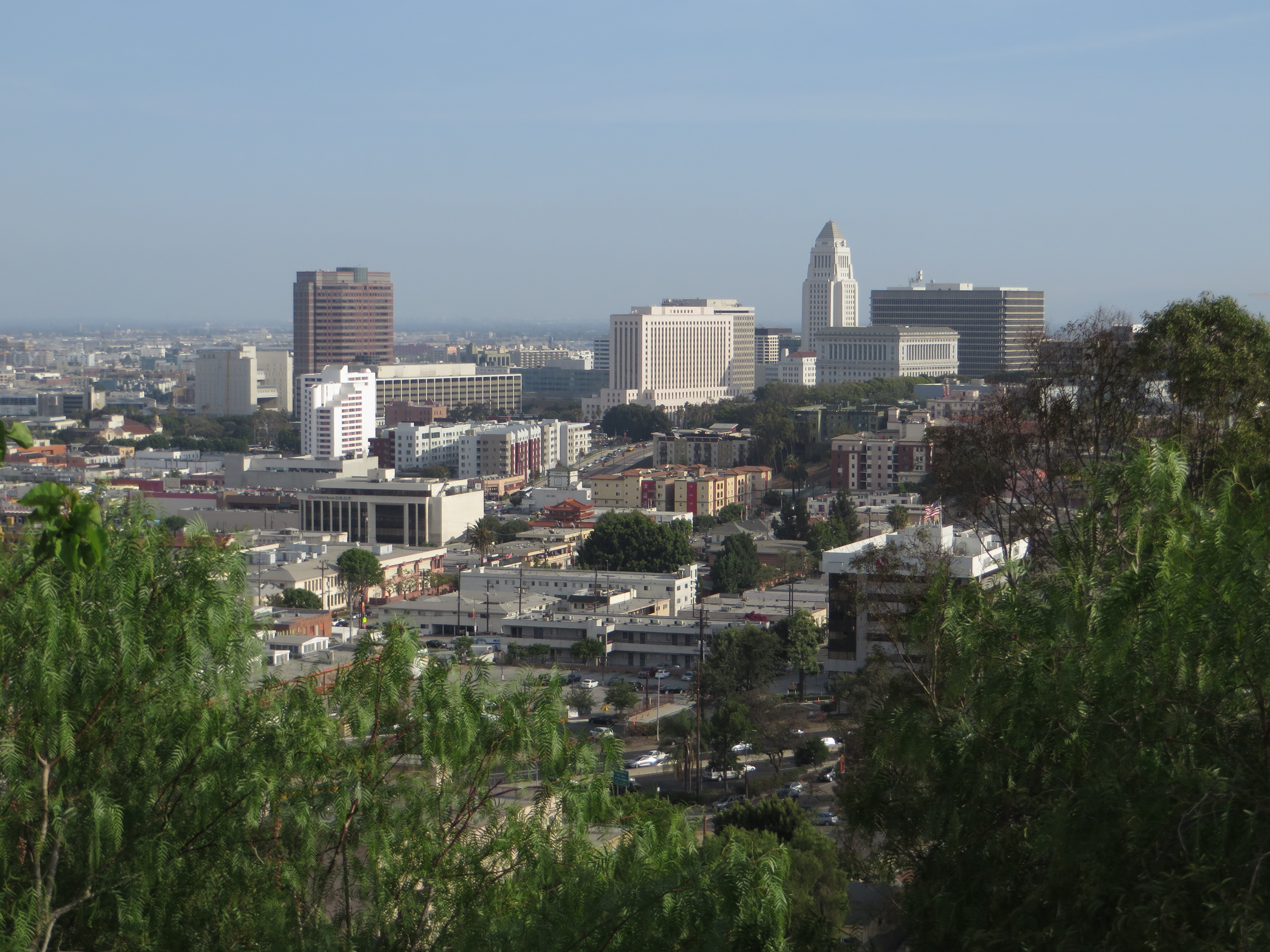 Aerial view of downtown Los Angeles with City Hall's white tower prominent among government buildings.