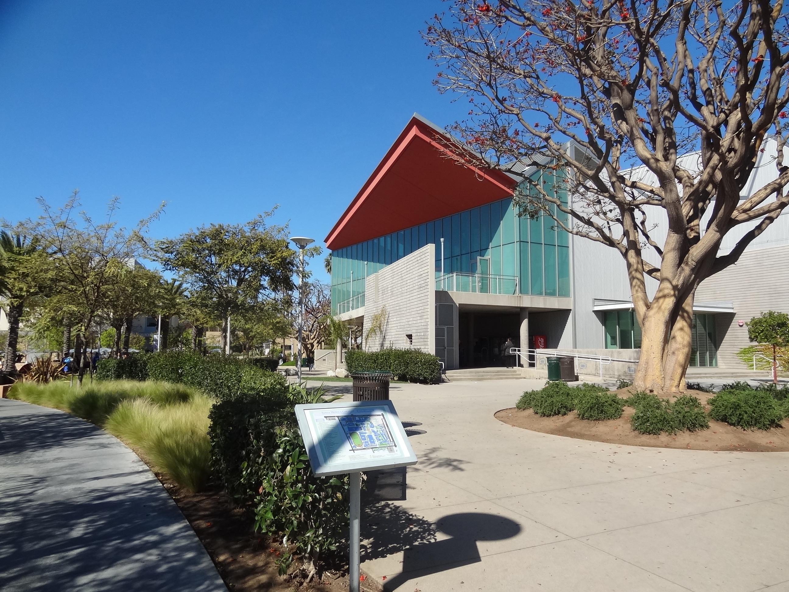 A modern theater arts building on a college campus with trees and walkway.