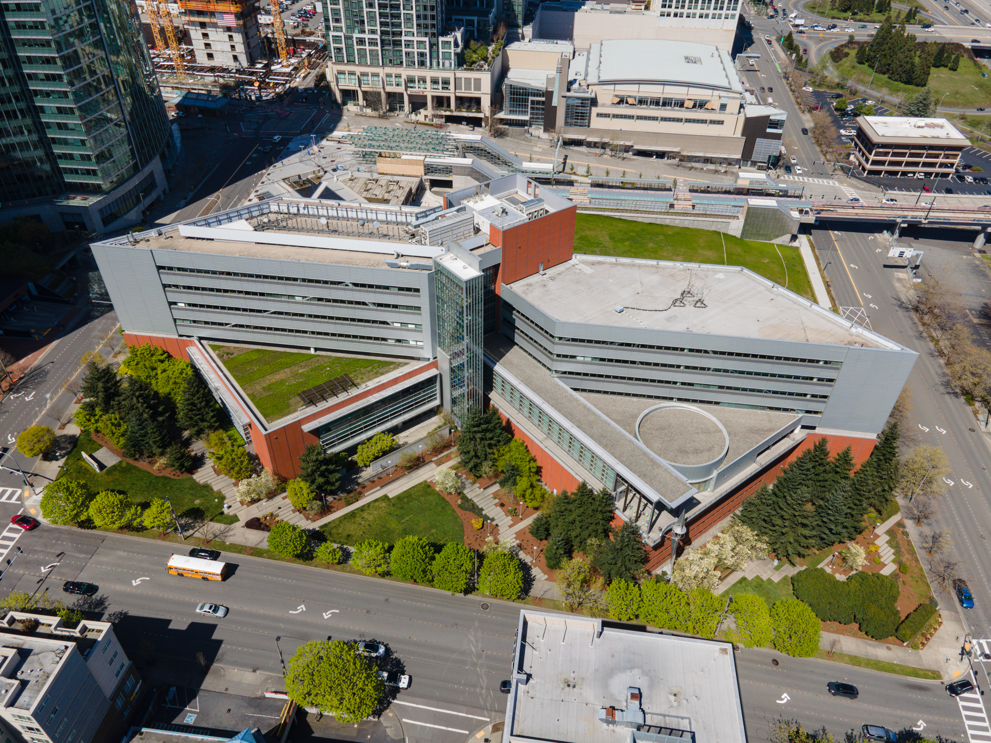 Aerial view of two large connected government buildings with green rooftops surrounded by trees.