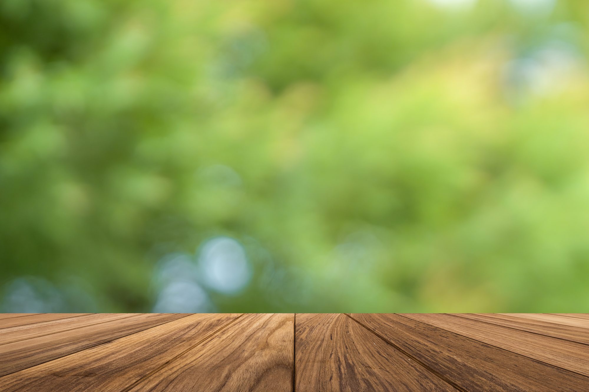 Wooden Tabletop Against Soft Green Nature Background with Blurry Foliage Effect