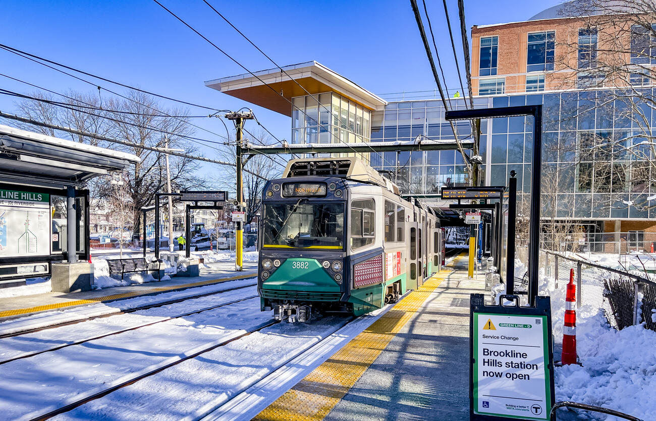 Green MBTA trolley stopped at a snowy Brookline Hills station platform.