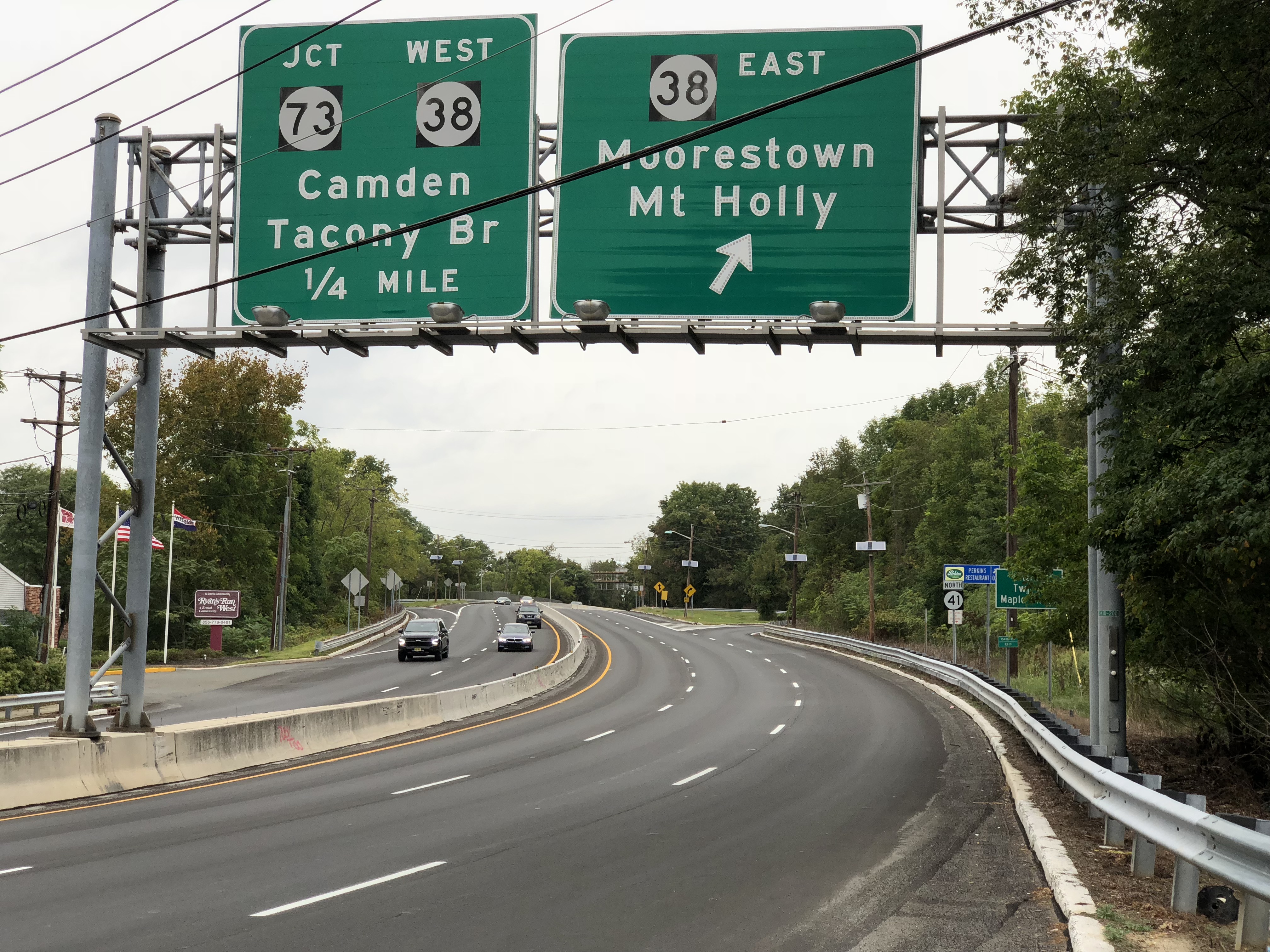 Green overhead highway signs indicating Route 38 East above a multi-lane road.