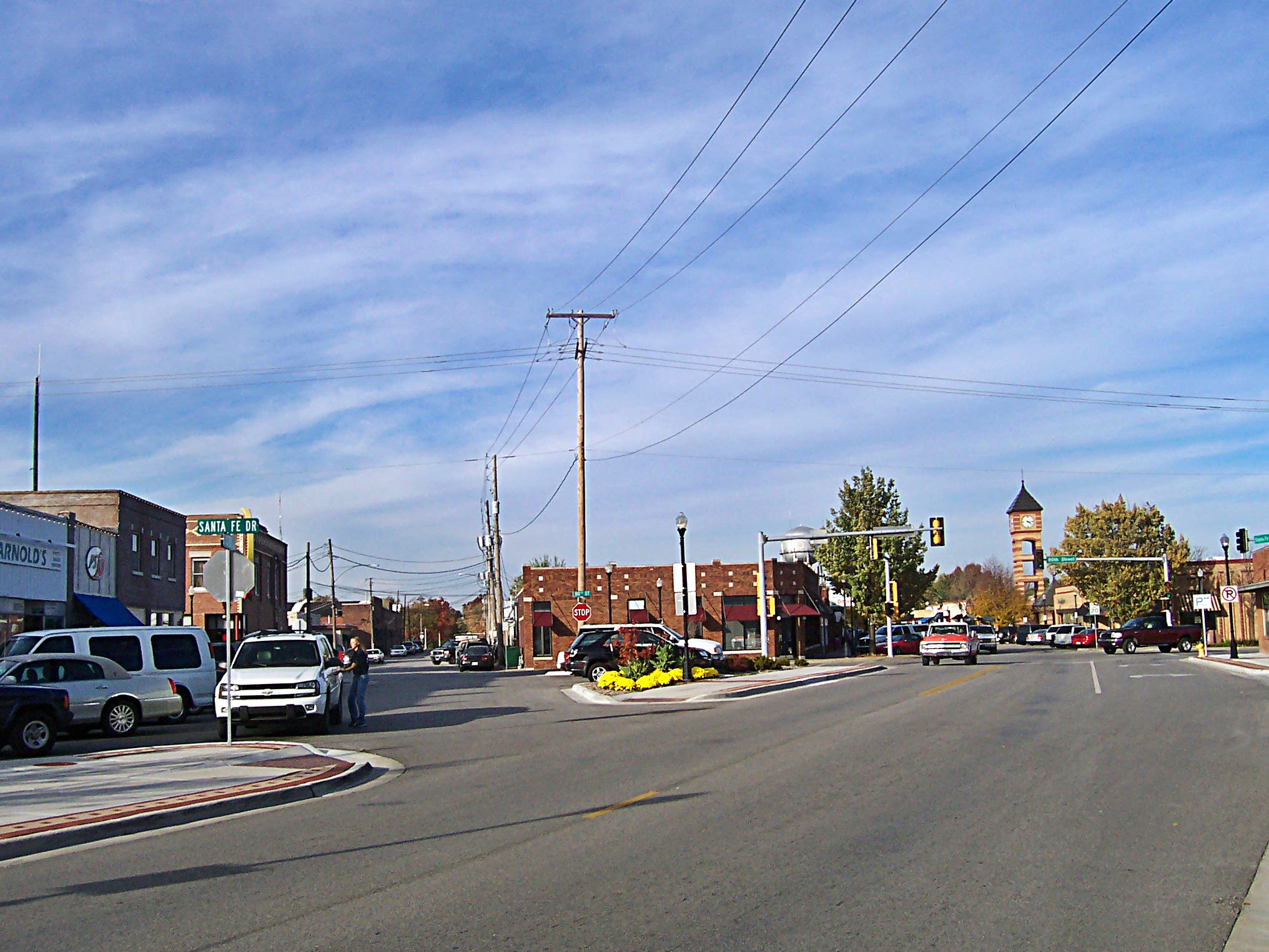 A two-lane downtown street lined with brick buildings and a clock tower in the background.