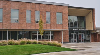 Two-story brick building with glass entrance doors and a sign reading Wacheno Welcome Center.