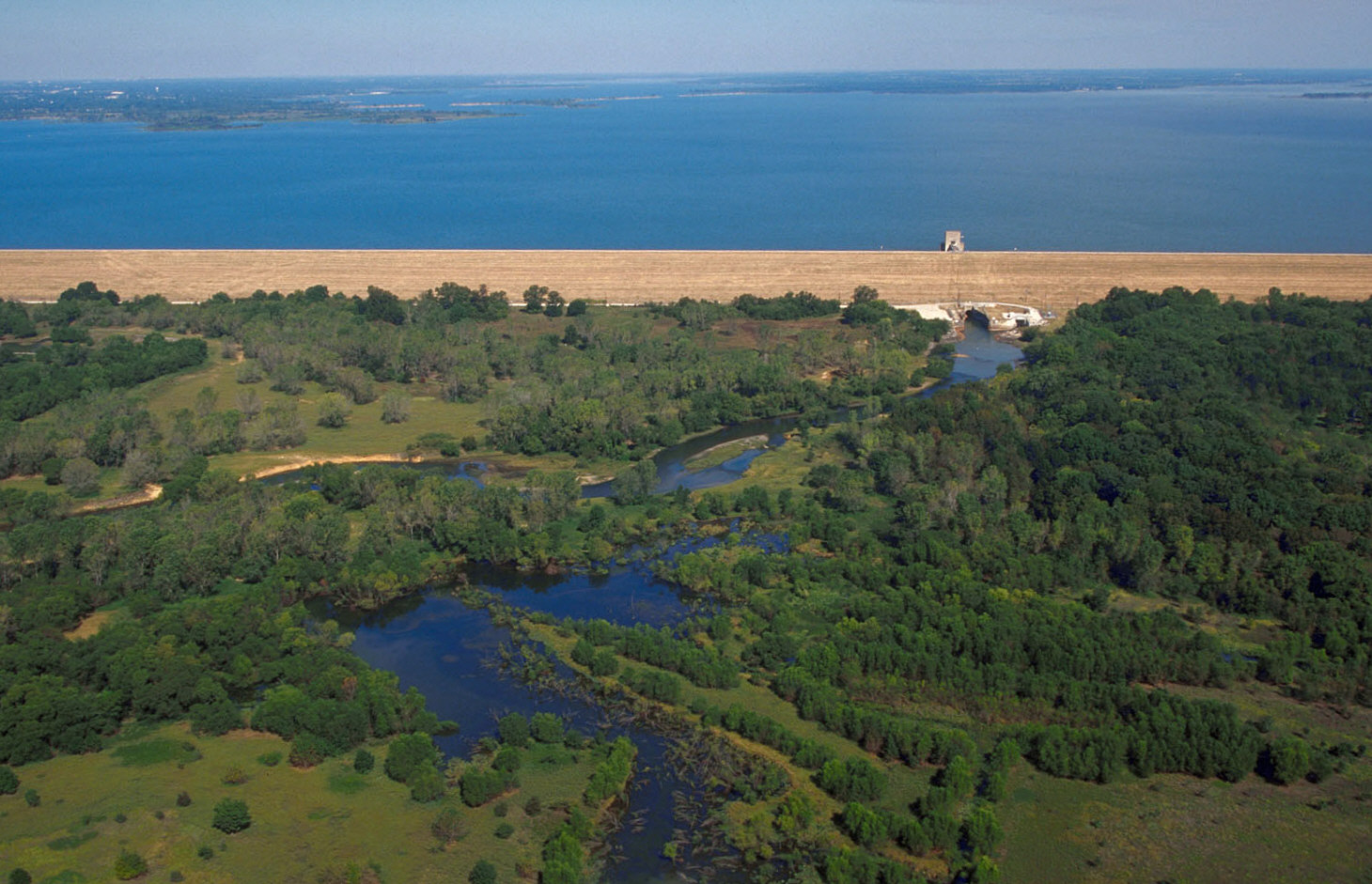 Aerial view of a large lake and dam surrounded by flat Texas terrain.