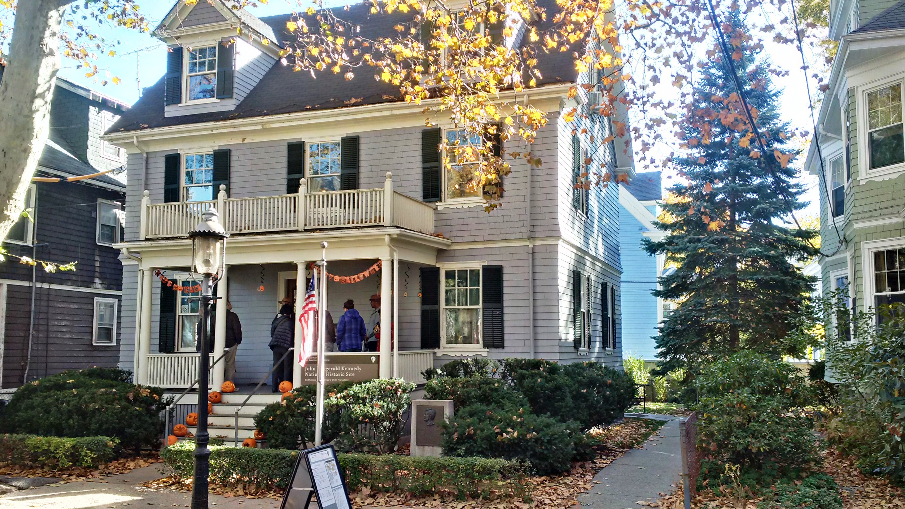 Gray Victorian house decorated with orange bunting and pumpkins for Halloween.