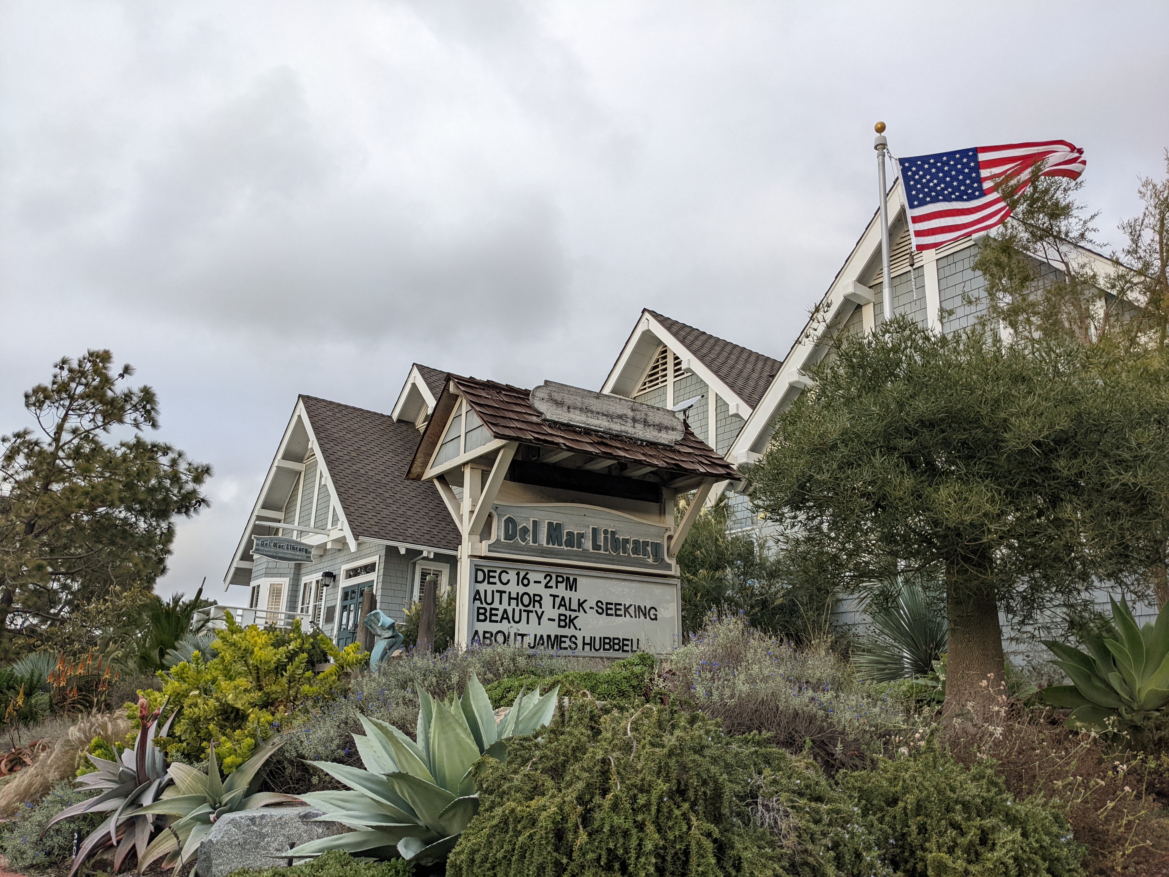 Exterior of a Craftsman-style library building with a gabled roof and event sign.