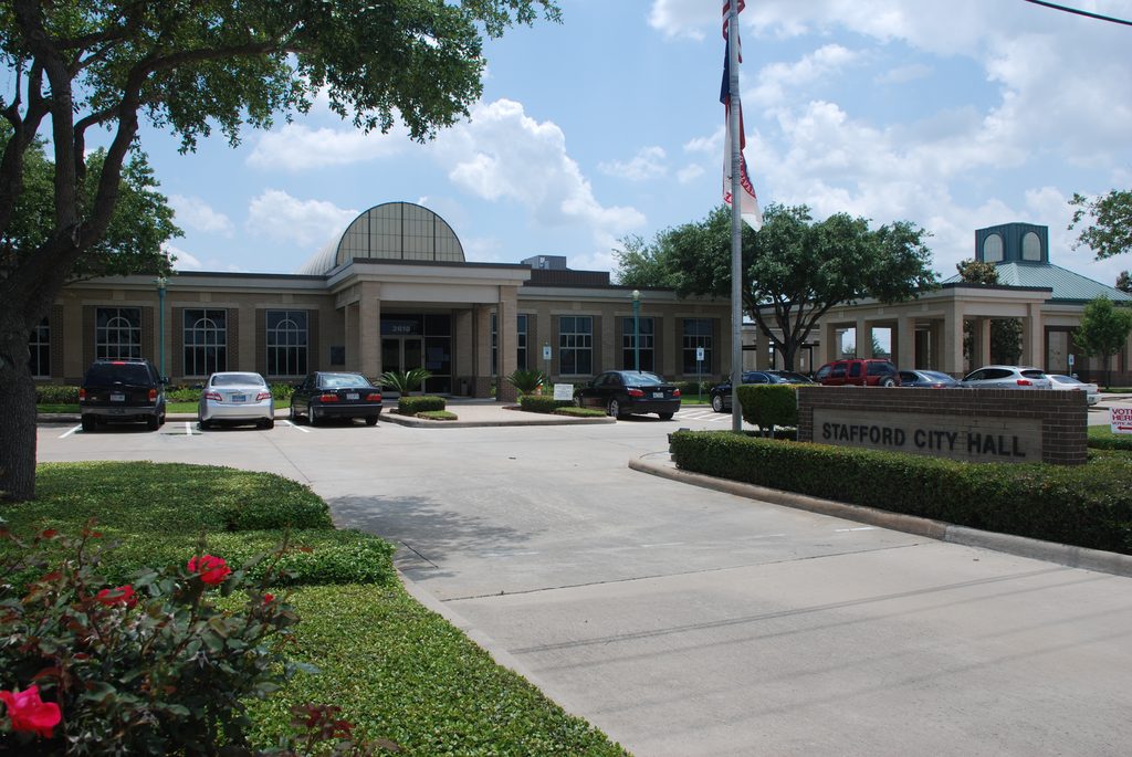 Exterior of Stafford City Hall building with flagpole and parking lot