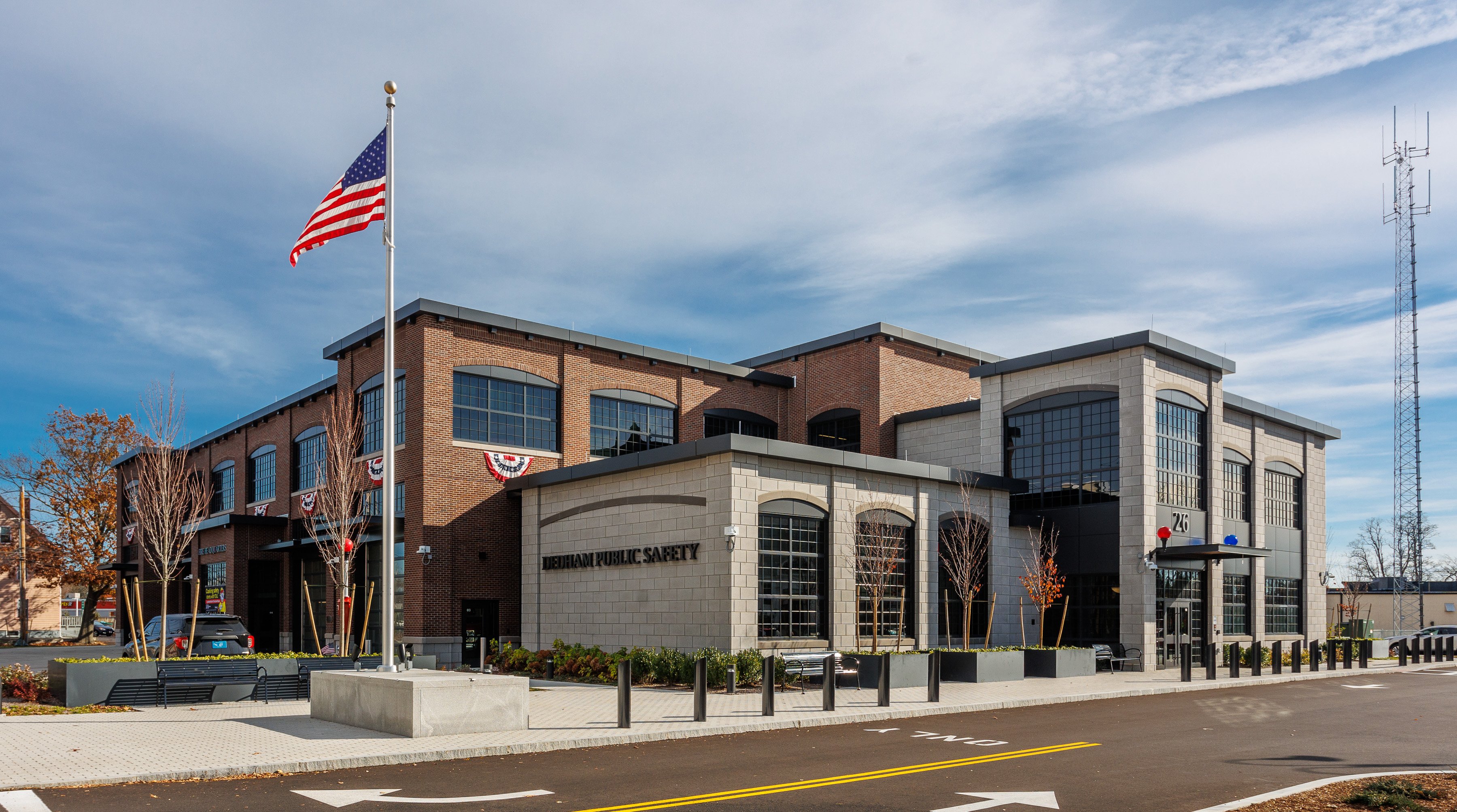 Modern brick public safety building with garage bays, flagpole, and communications towers.