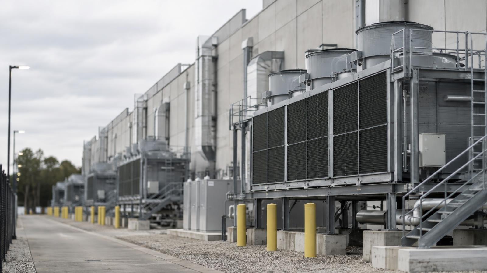 Large industrial building exterior with rows of cooling units and ventilation equipment along its facade.