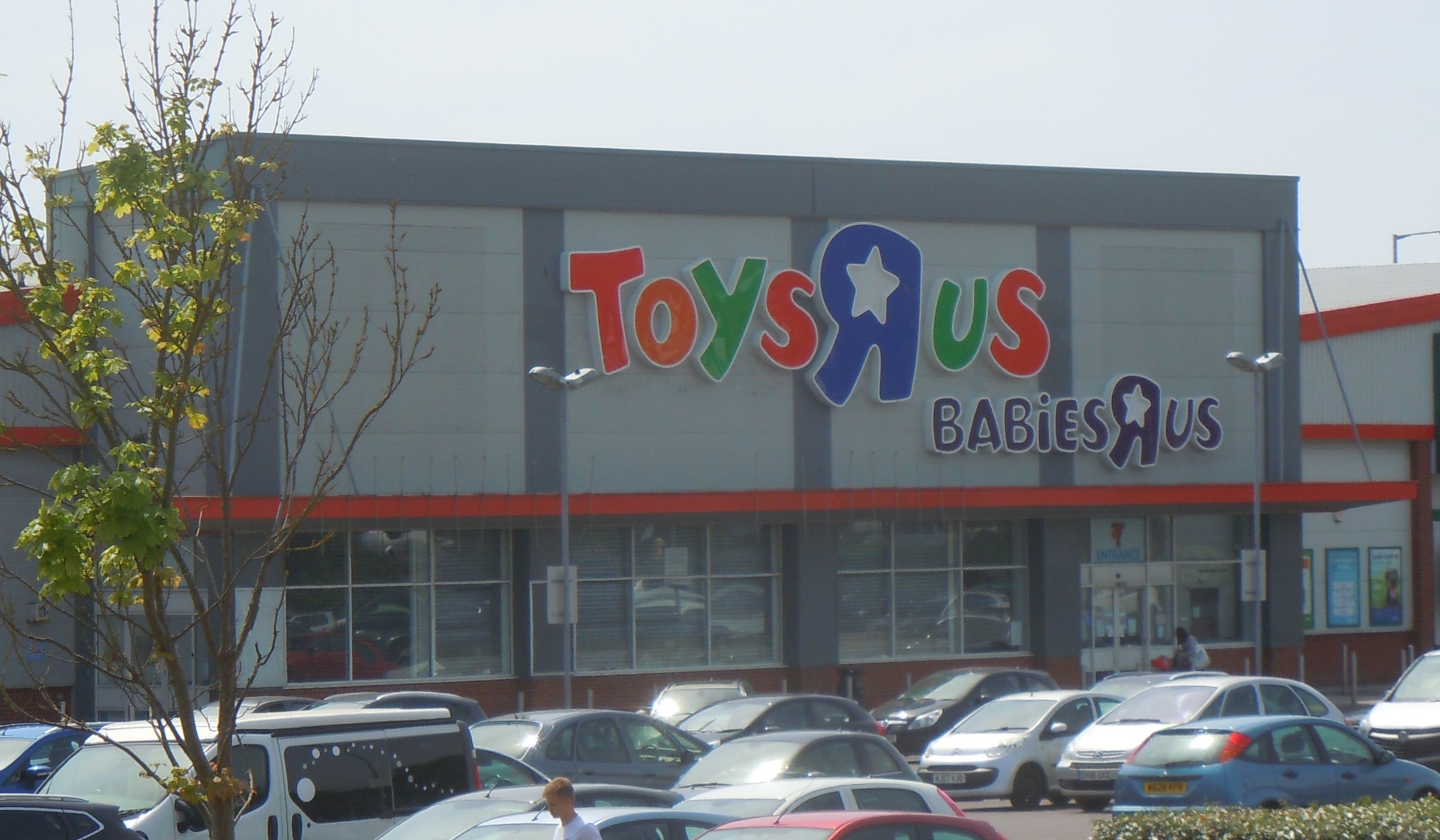 Wide-angle view of a retail store with Toys R Us and Babies R Us signage and a full parking lot