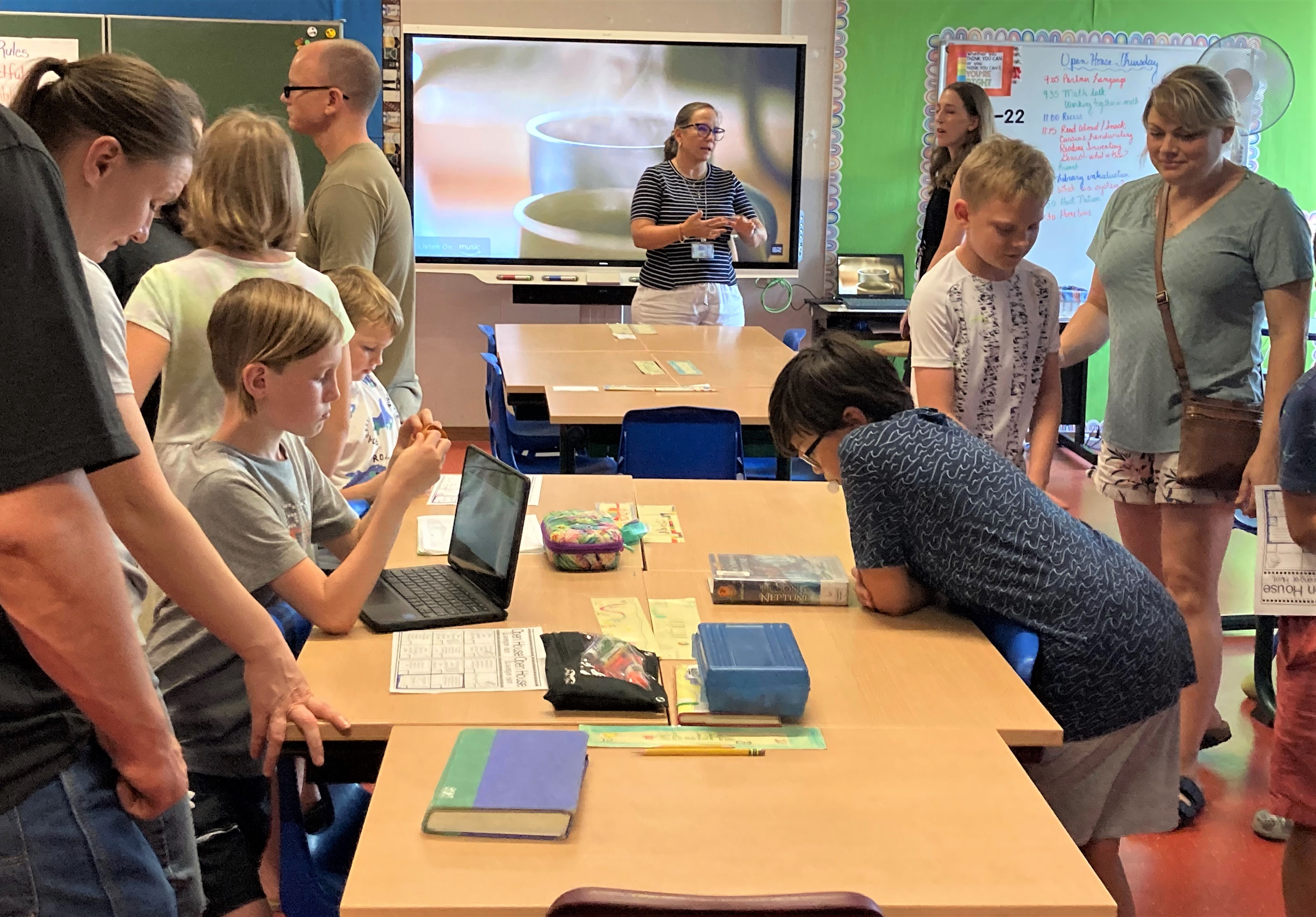 Adults and children gathered in a decorated classroom during a school open house event.