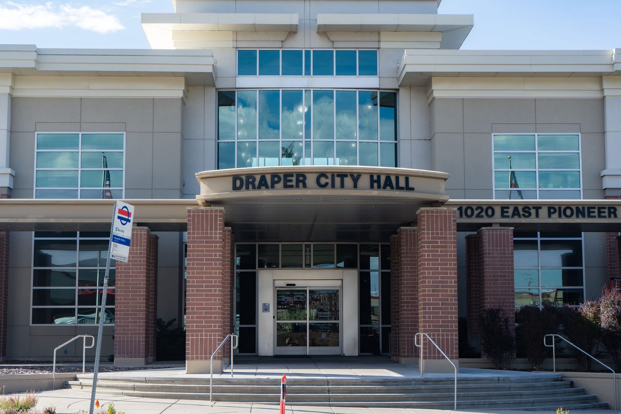 Front entrance of a modern brick and glass municipal building with prominent signage.