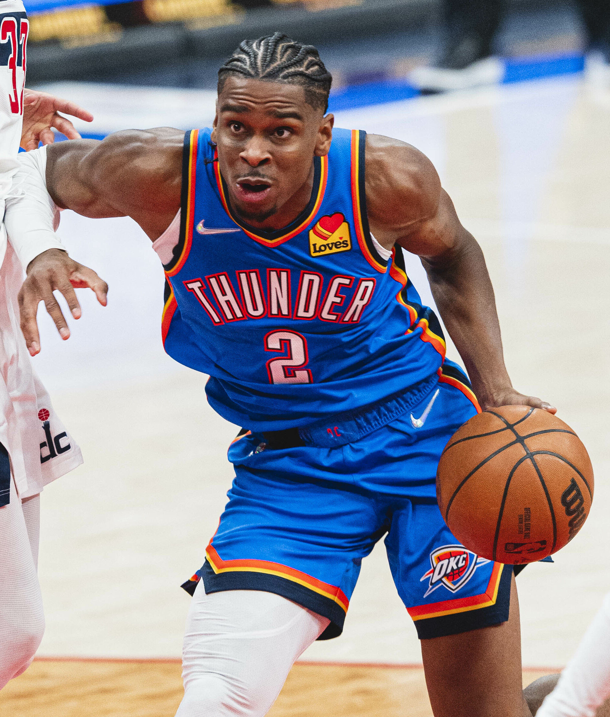 Thunder player in blue jersey number 2 dribbles basketball during an NBA game.