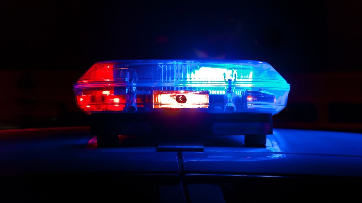Red and blue police emergency lights illuminated on a vehicle at night.