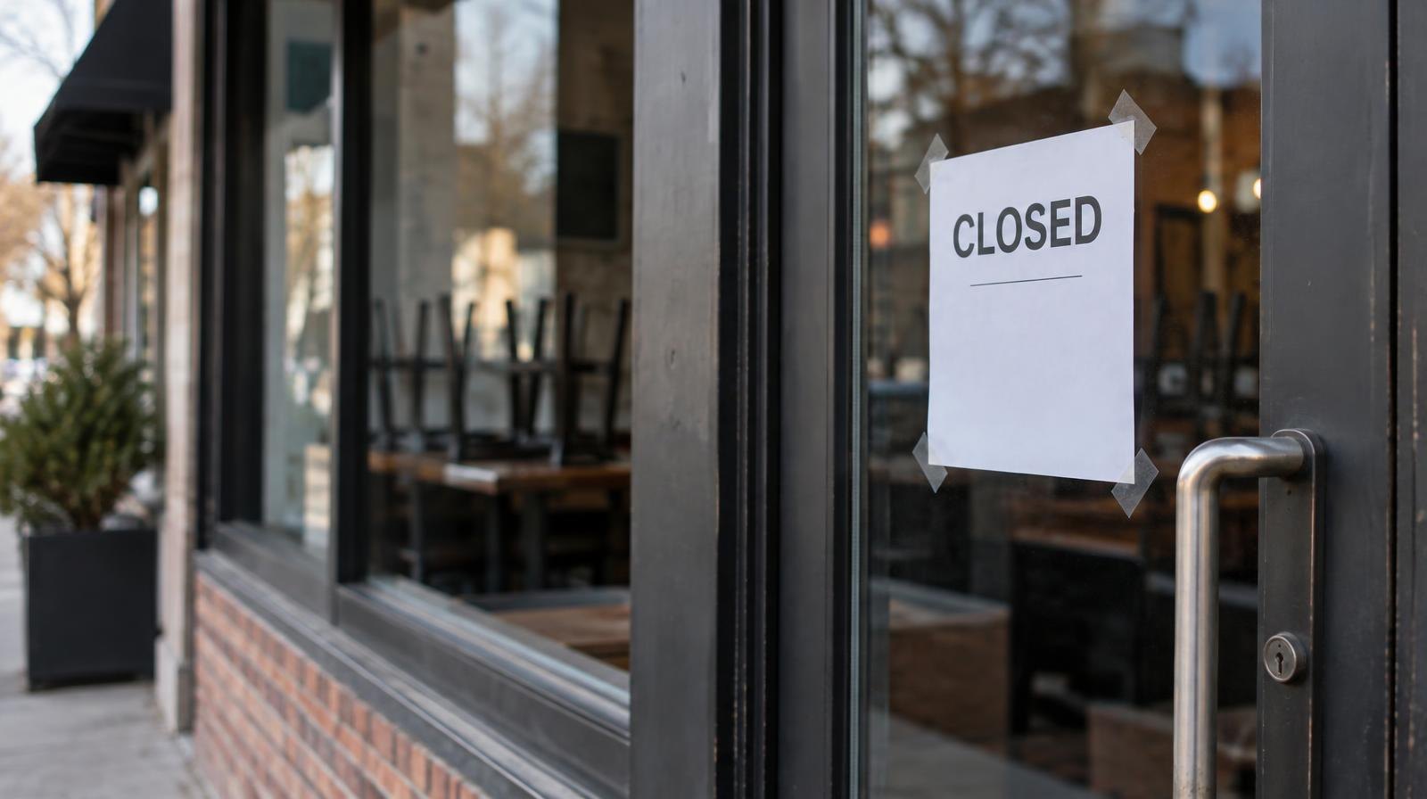 Closed restaurant storefront with a paper notice on the glass door.