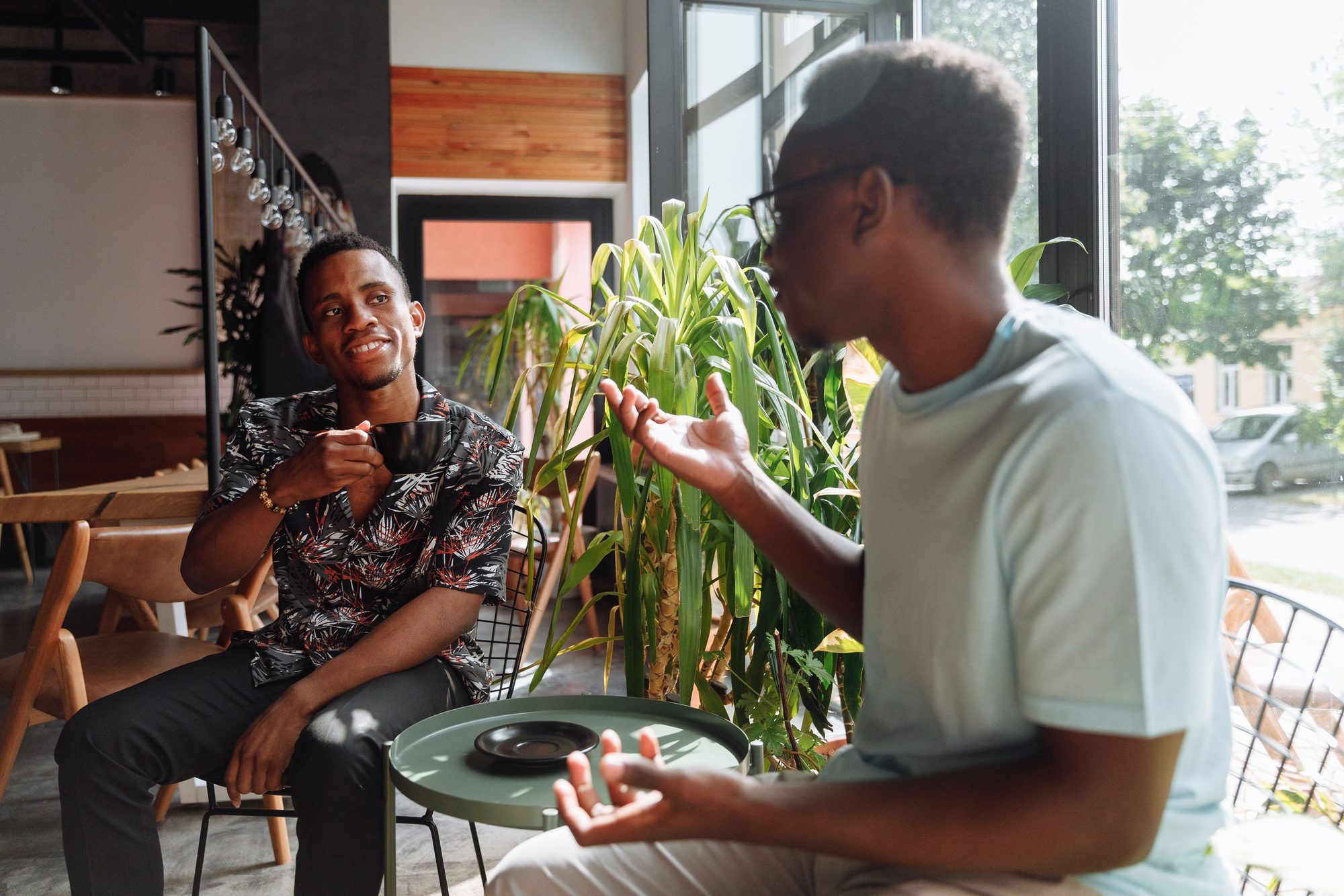Two friends having a lively conversation over coffee in a cozy coffee shop setting.