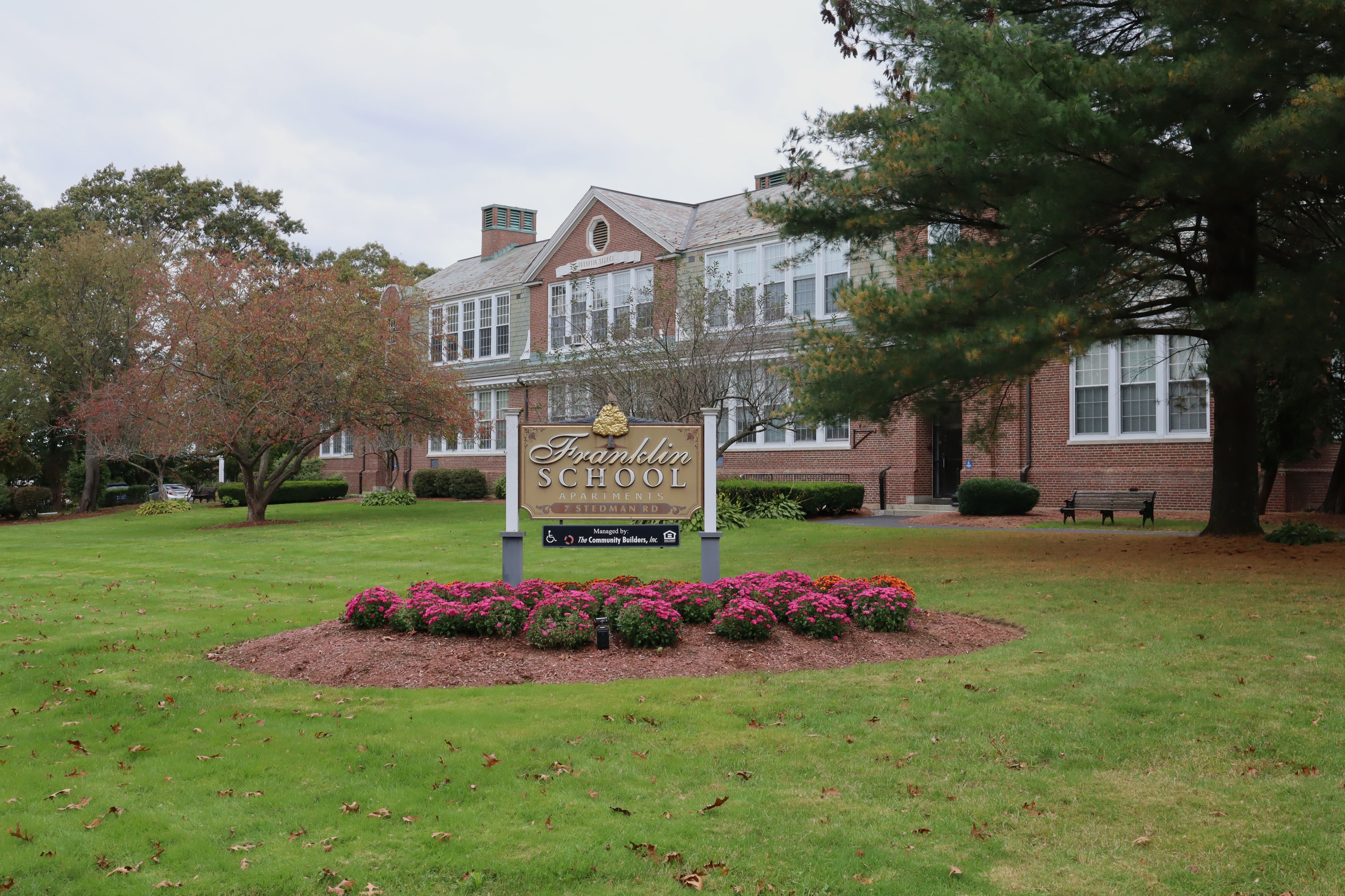 Red brick school building with a sign reading Franklin School on a green lawn.