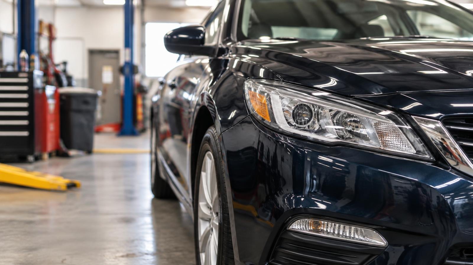 A gleaming car with polished paint parked in a bright automotive service bay.