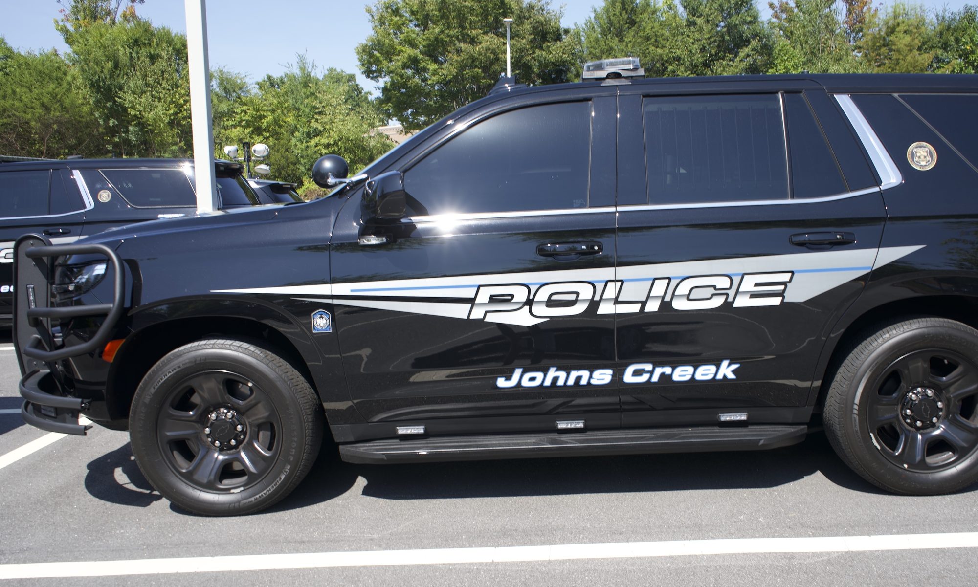 Black marked police SUV with light bar and push bumper parked in a lot