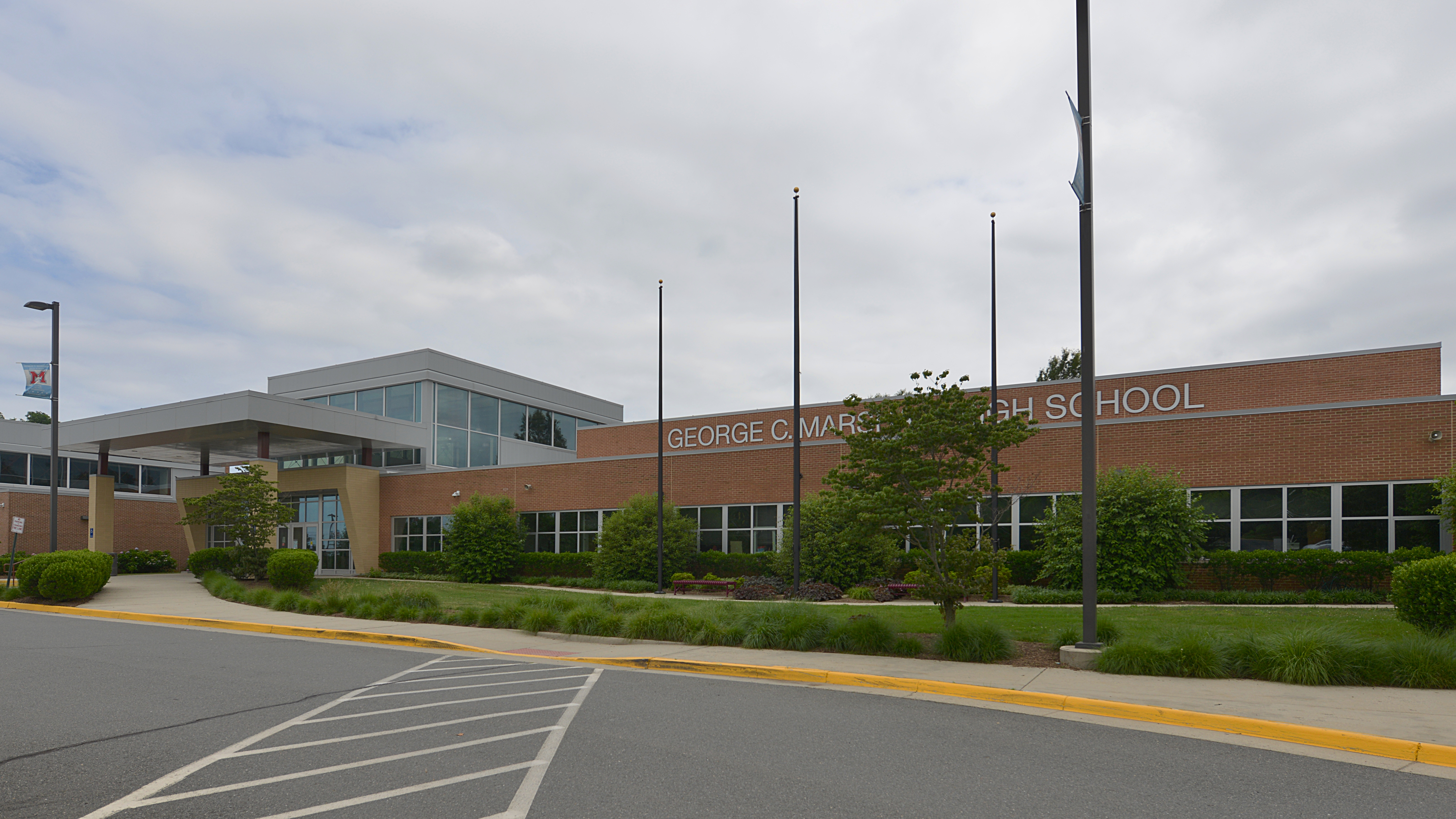 Brick facade and entrance of George C. Marshall High School with flagpoles and landscaping.