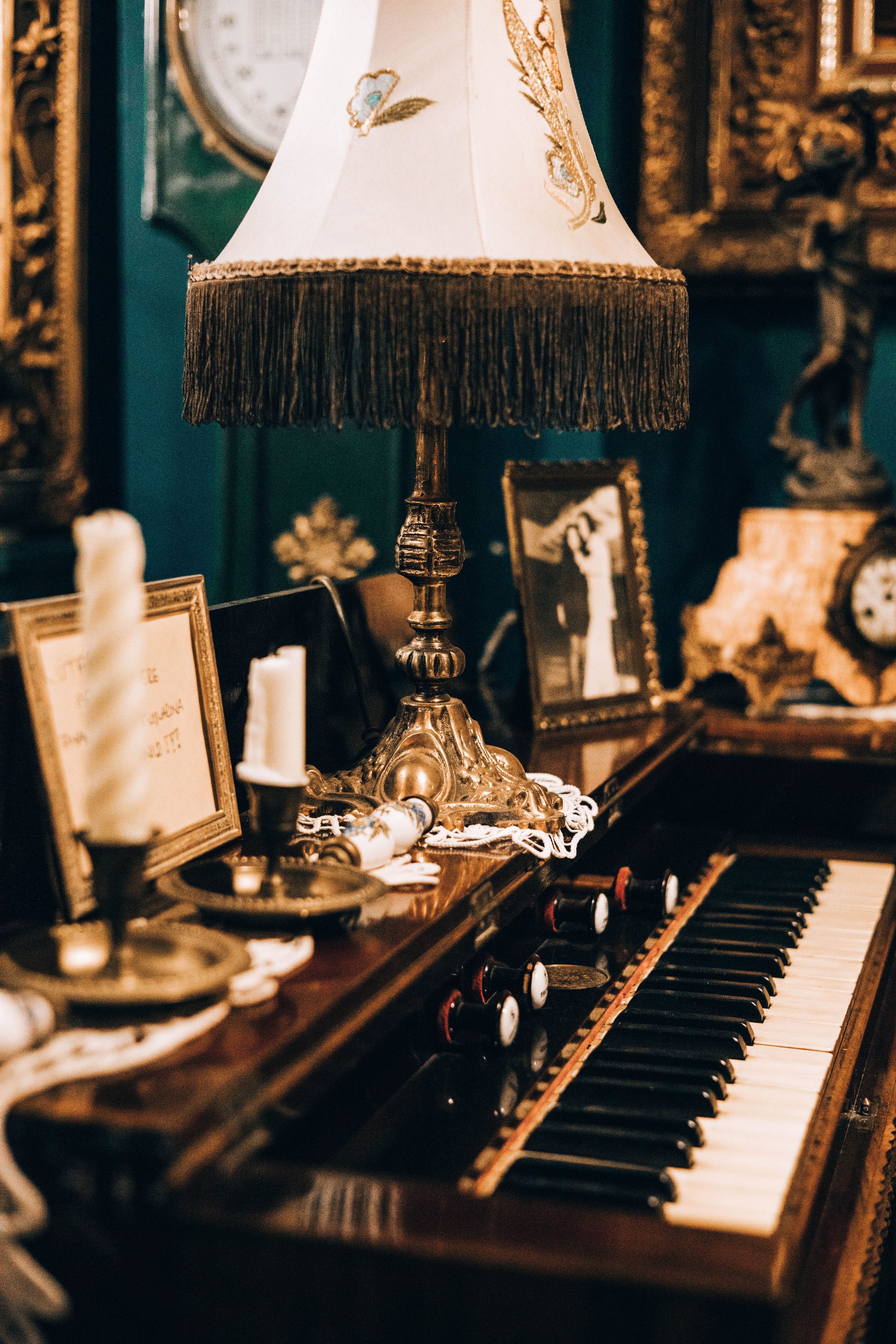 A vintage piano with an ornate lamp surrounded by antique decor, evoking historical elegance.