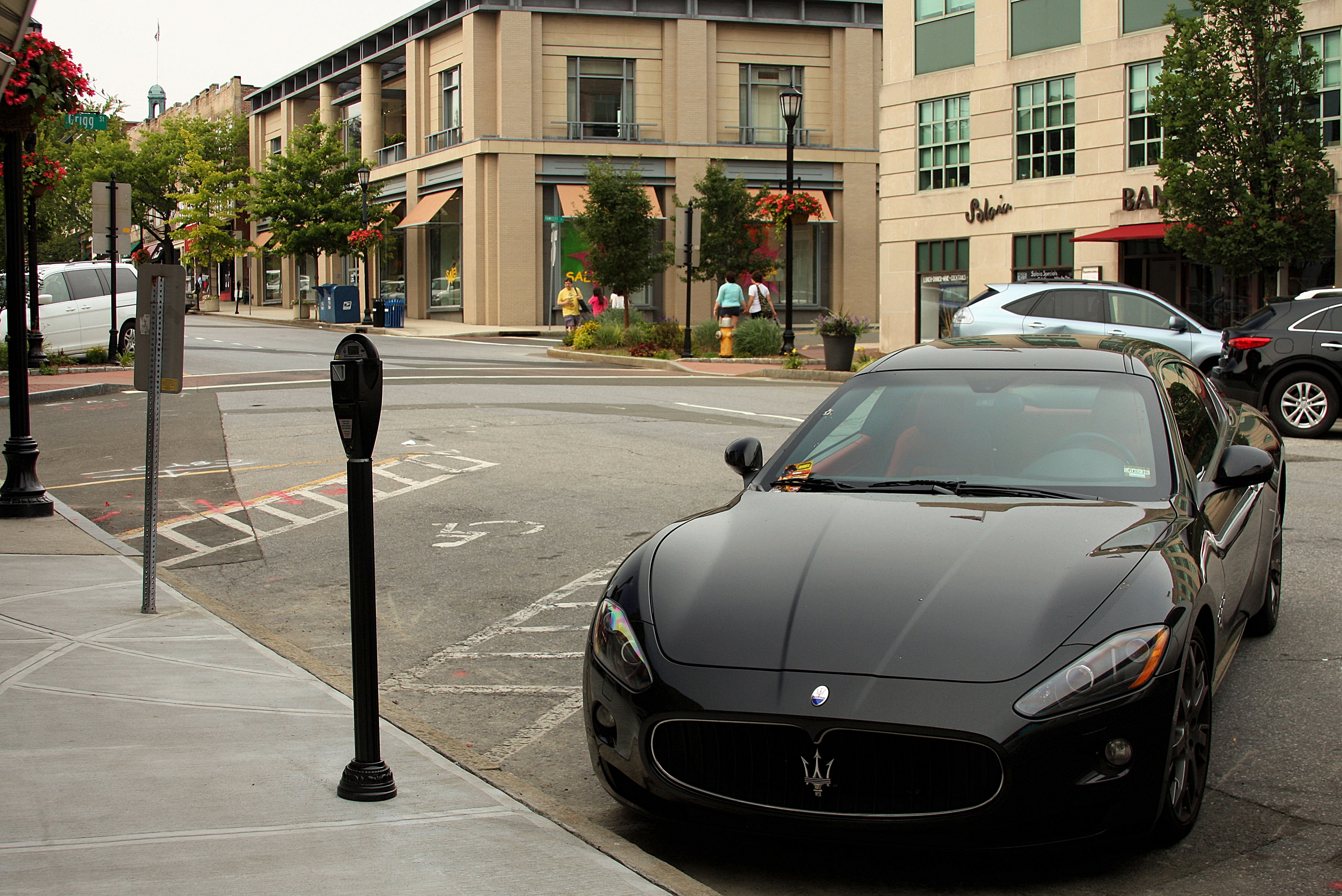 A car parked at a coin-operated parking meter on a downtown street.