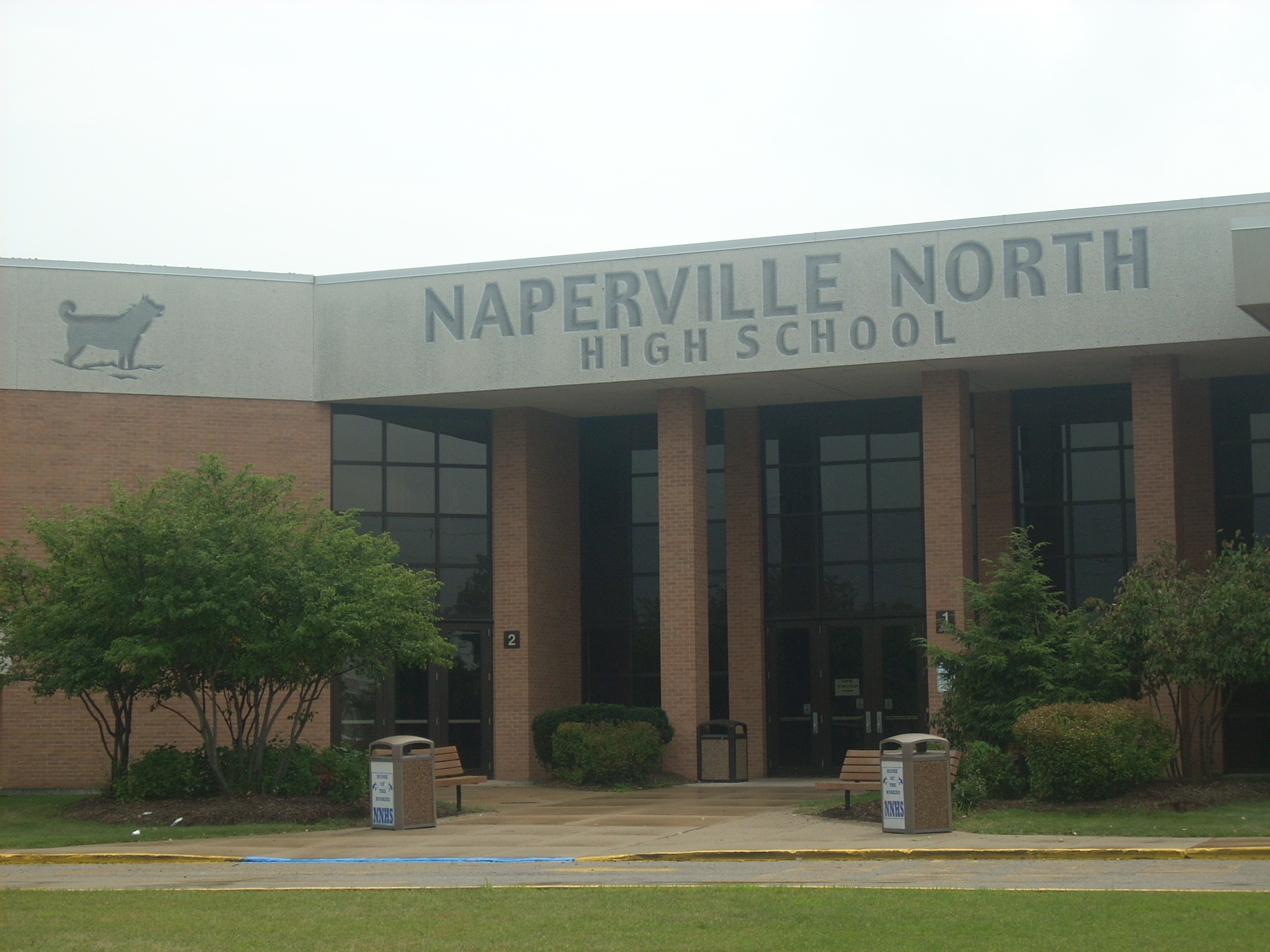 Brick facade of Naperville North High School with school name and husky mascot logo.
