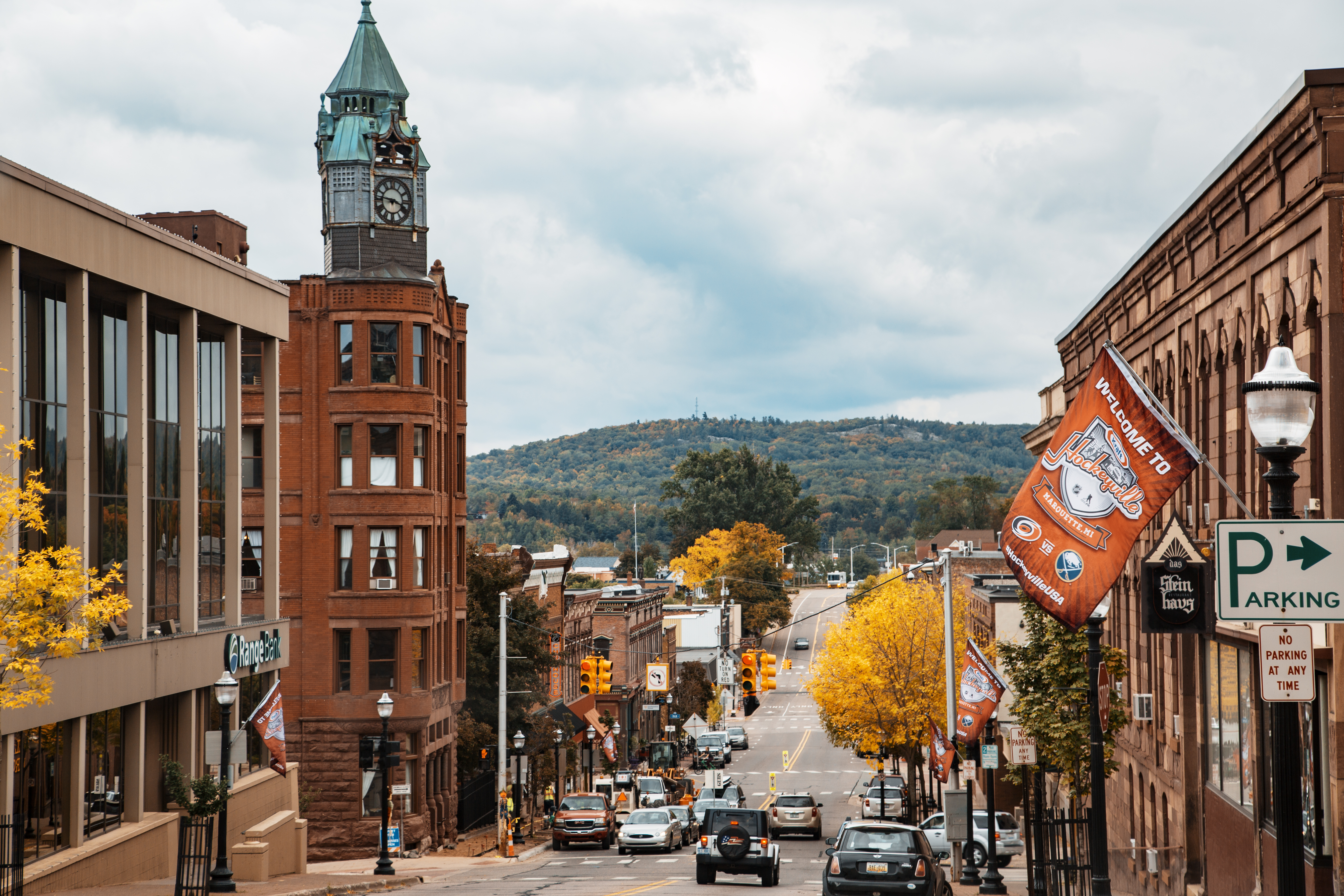 Downtown street in Marquette, Michigan with a brick clock tower and autumn foliage.