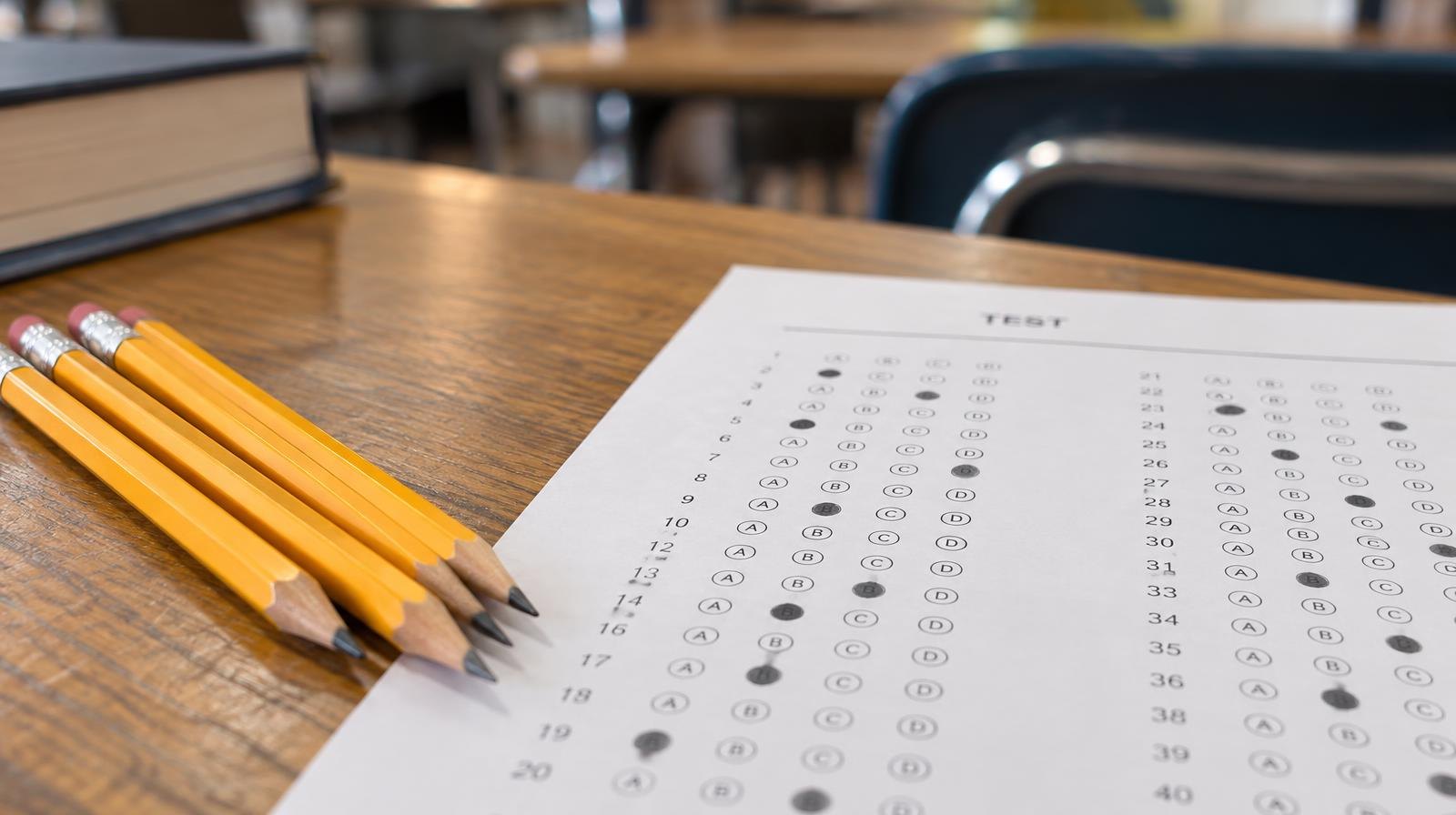 Sharpened pencils and a bubble-filled answer sheet resting on a wooden school desk.