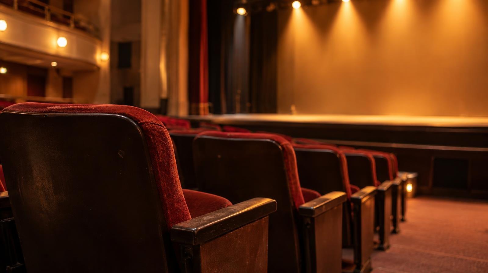 Rows of theater seats facing a warmly lit empty stage.