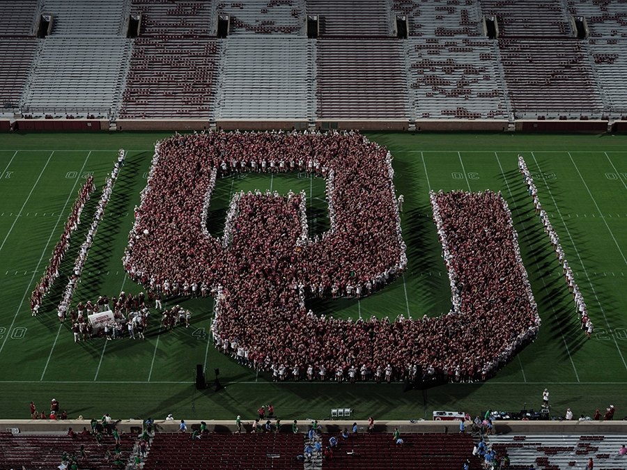 Thousands of students form a giant OU logo on a football field, viewed from above.