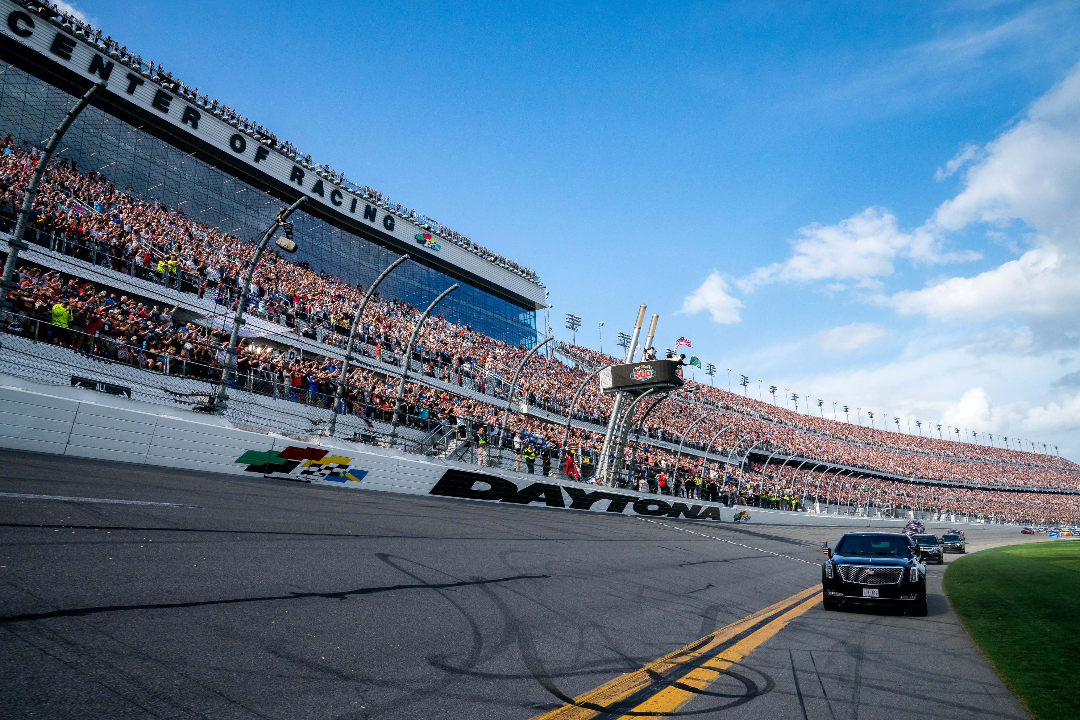 Packed grandstands at Daytona International Speedway with a vehicle on the track below.