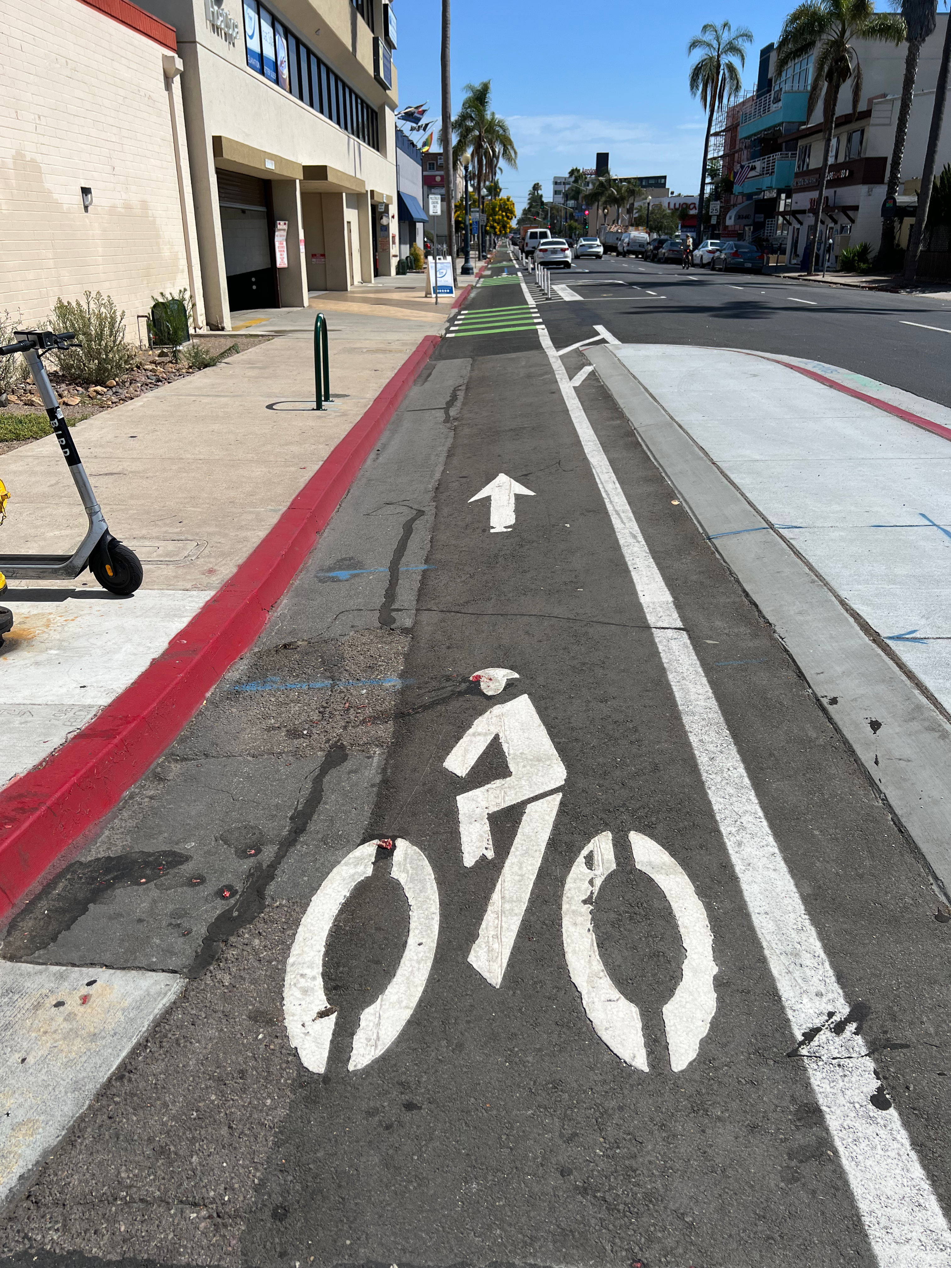 White bicycle symbol and arrow painted on a dedicated bike lane along an urban street.