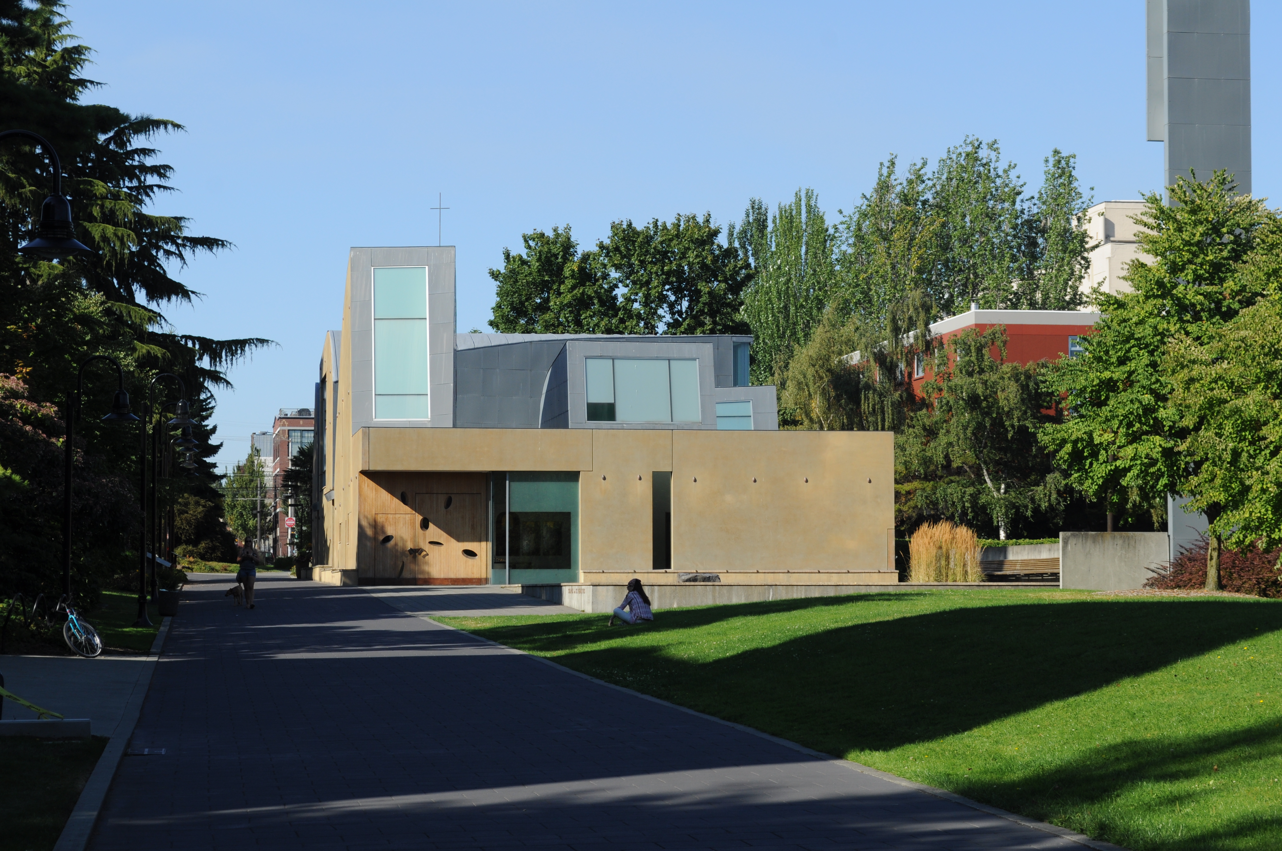 Modernist building with geometric forms, glass windows, and a tall tower on a green campus lawn.